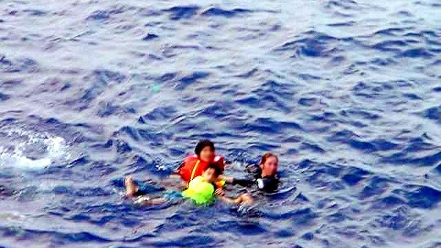 In this file photo, an Australian Navy officer (R) rescues two refugee children from the sea off Christmas Island, on October 10, 2001. The rescue authorities on Sunday said a search for eight people missing after a boat carrying 97 asylum-seekers sank in remote seas had ended, with little chance anyone would be found alive.