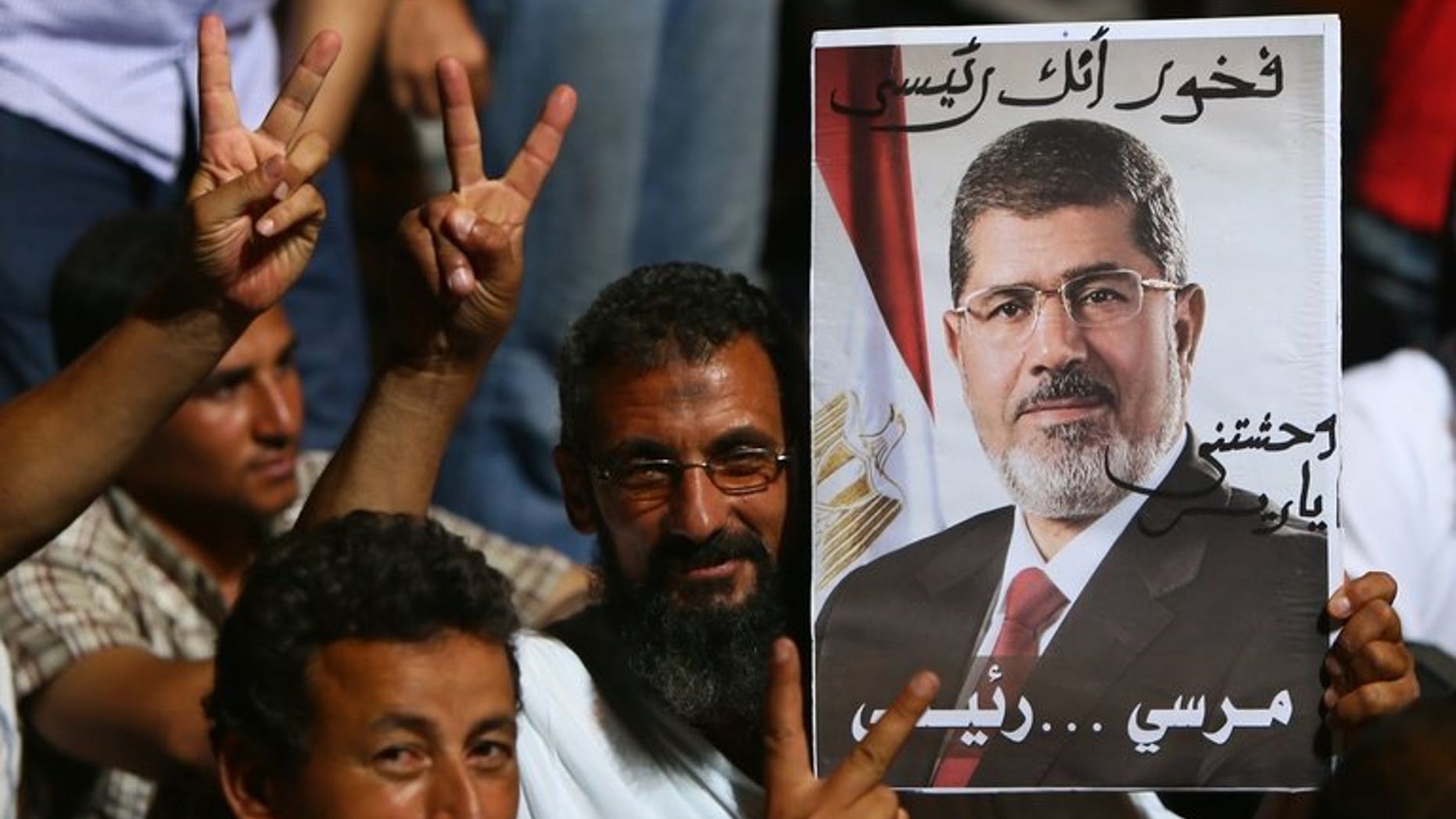 Supporters of deposed Egyptian president Mohamed Morsi flash the victory sign during a rally outside Cairo's Rabaa al-Adawiya mosque on June 10, 2013.