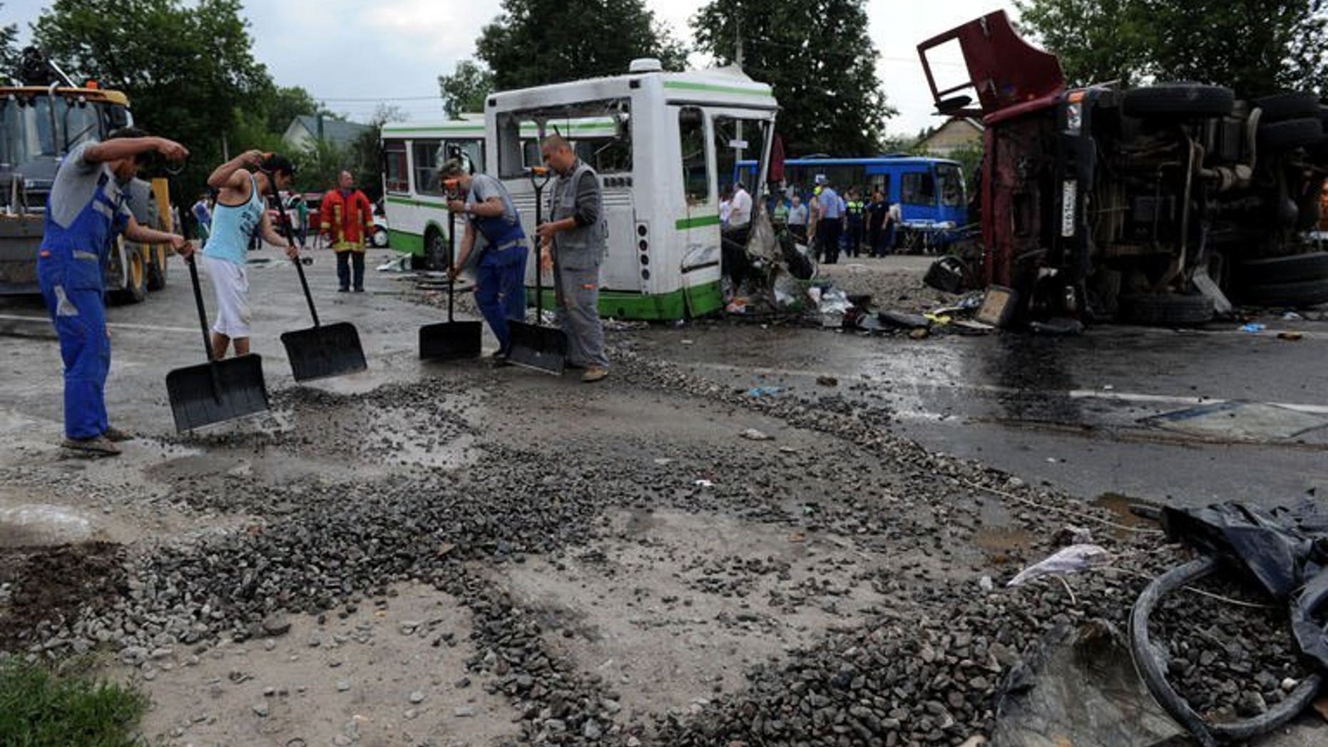 Men clear the crash scene near the village of Oznobikhino, on July 13, 2013. Russian investigators have interrogated the hospitalised driver of a truck that ploughed into a packed passenger bus outside Moscow killing 18 people.