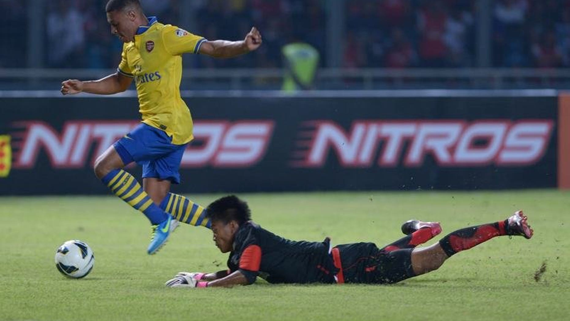 Arsenal's striker Alex Oxlade-Chamberlain (L) vies with Indonesia's goalkeeper Kurnia Meiga during a friendly football match Arsenal FC vs Indonesia Dream Team in Jakarta on July 14, 2013. Arsenal won 7-0.