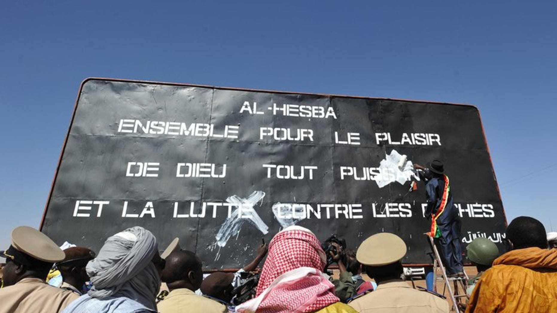 Men watch on January 30, 2013, as the mayor of the Malian city of Gao paints over a billboard left by MUJAO, an offshoot of AQIM. A Mauritanian court on Sunday freed a Canadian jailed for attempting to join an Al-Qaeda training camp in neighbouring Mali, a judicial source said.