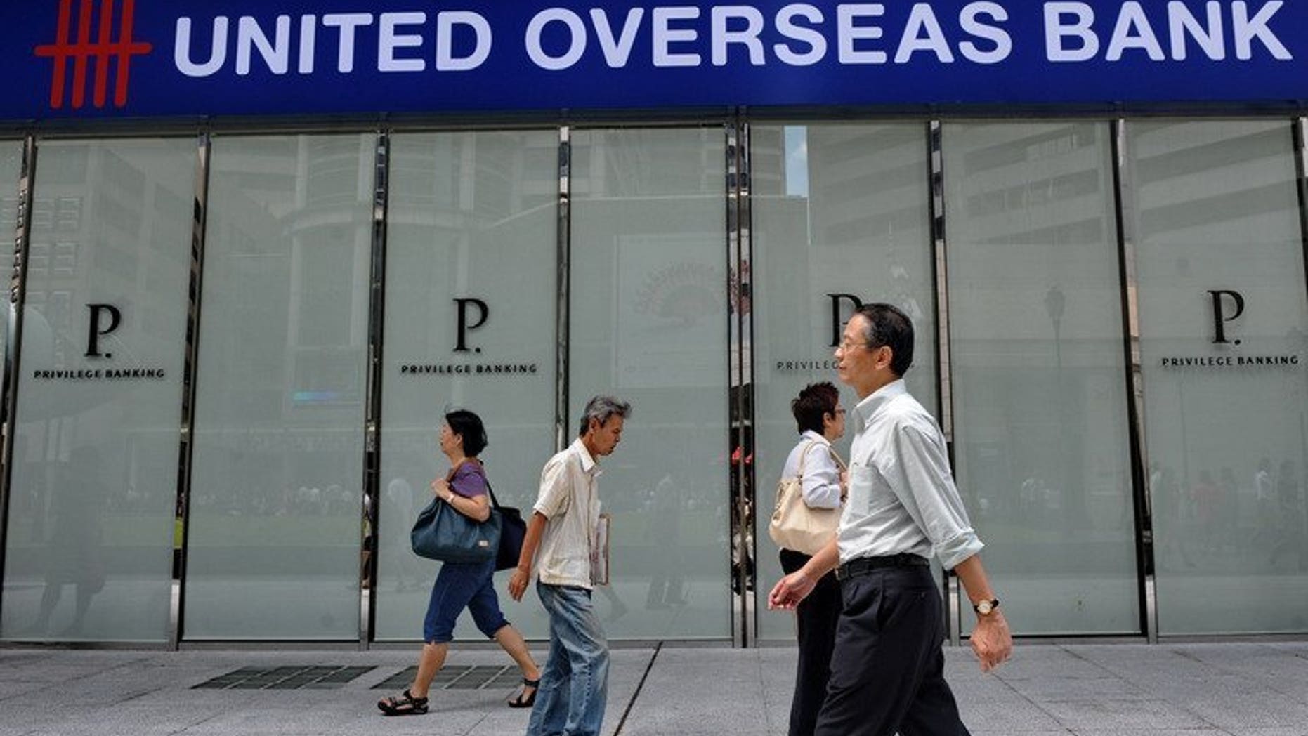 People walk past an outlet of United Overseas Bank during lunch hour in Singapore on February 9, 2012. Credit rating agency Moody's on Monday downgraded the outlook of Singapore's three main banks -- DBS Bank, Oversea-Chinese Banking Corp. and United Overseas Bank -- to "negative" from "stable" amid rising property prices and mounting household debt in the city-state.