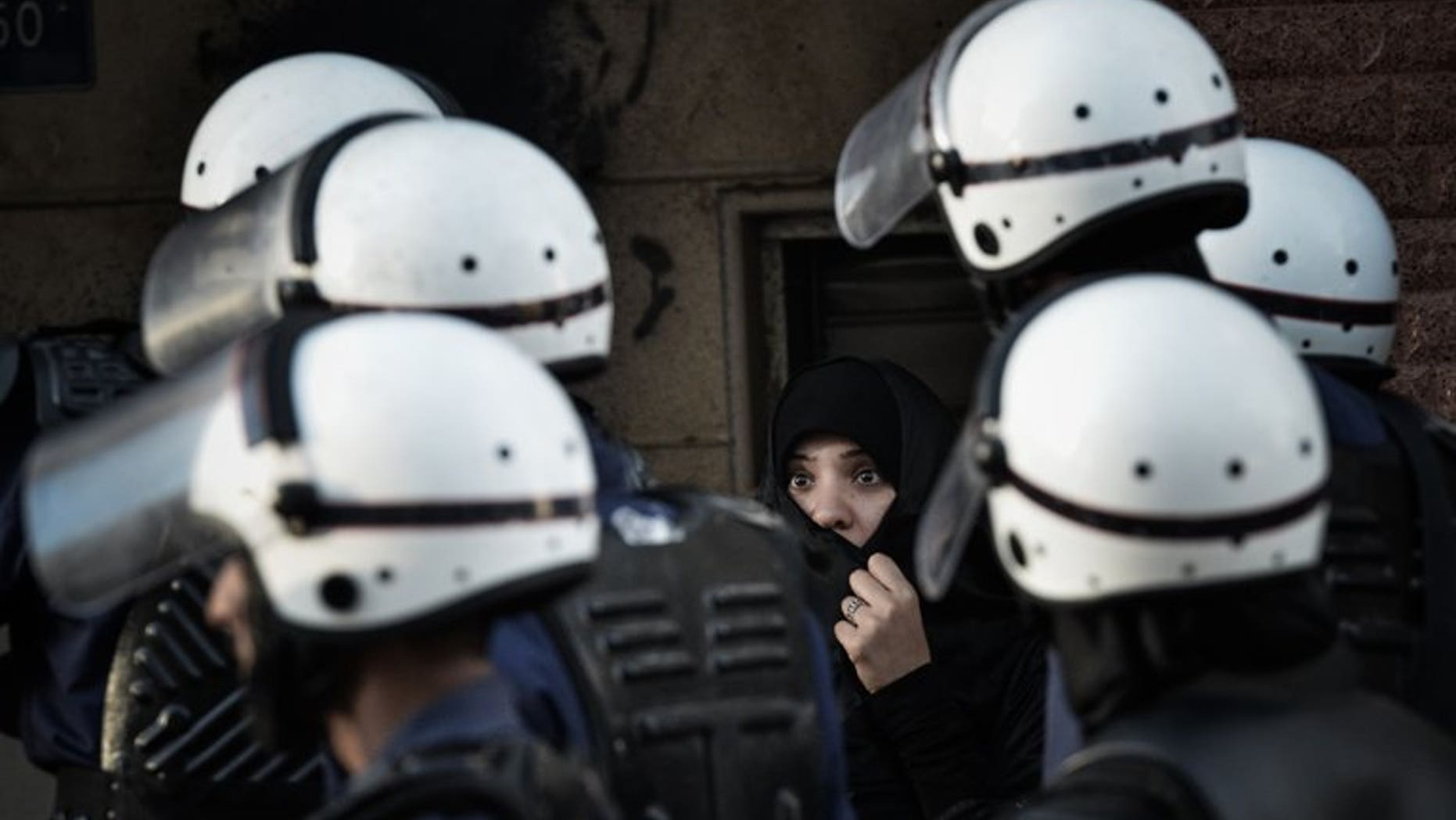 Bahraini police officers walk past a woman in Manama on January 18, 2013. Assailants hurled firebombs at the home of a Shiite lawmaker in Bahrain, without causing any casualties even though his family was inside at the time, parliament said.
