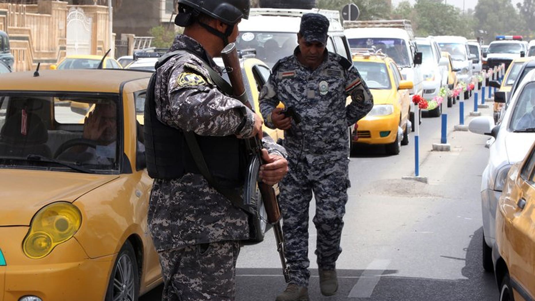 Iraqi security officers keep watch at a checkpoint in Baghdad on May 29, 2013. Four people were killed and nine wounded when a group of people were struck by mortars as they gathered for a swim on a bank of the Tigris river north of Baghdad