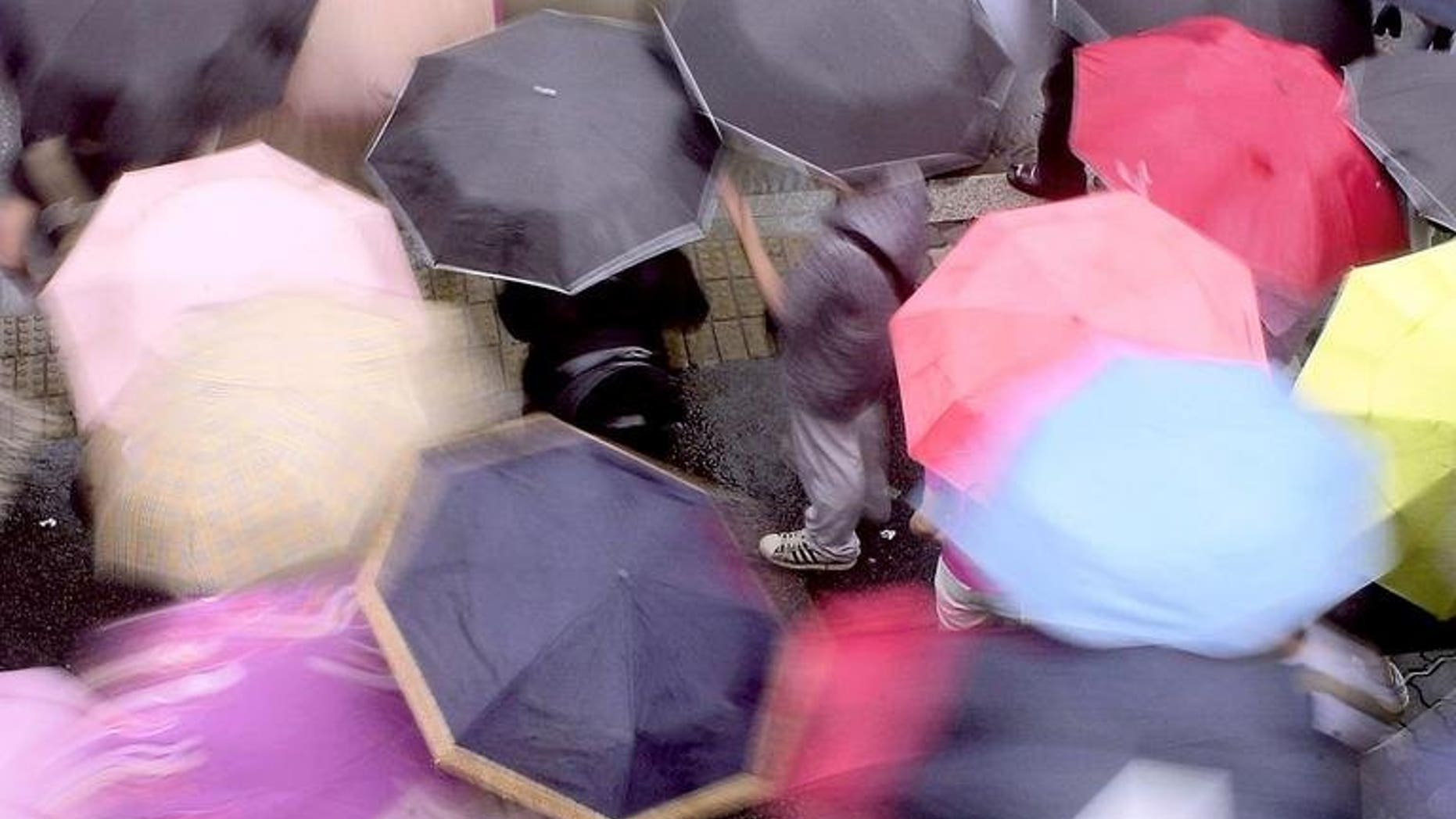 South Koreans carry colorful umbrellars as they cross a street in Seoul, on May 28, 2004. Three South Koreans have been confirmed dead or missing after heavy rains pounded the Korean peninsula, leaving hundreds homeless as the downpours left a trail of destruction in the two Koreas.