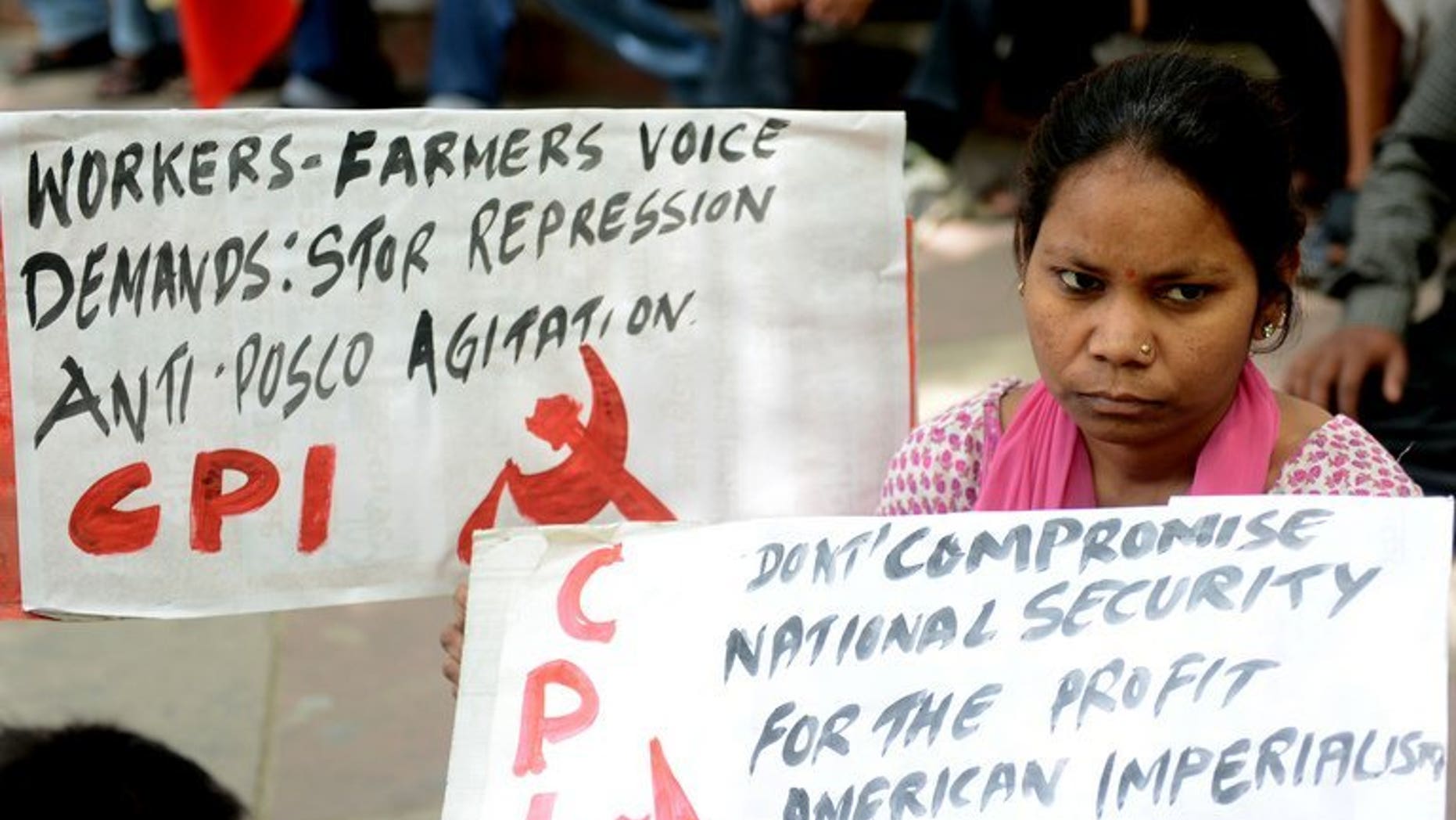 A woman holds an anti-US, South Korean and Indian government placard during a protest in New Delhi on April 12, 2013 against farmland being converted into an industrial development area by South Korean steel giant Posco. Posco said Tuesday it would scrap a $5.3 billion deal to build a steel plant in India because of delays and local opposition.