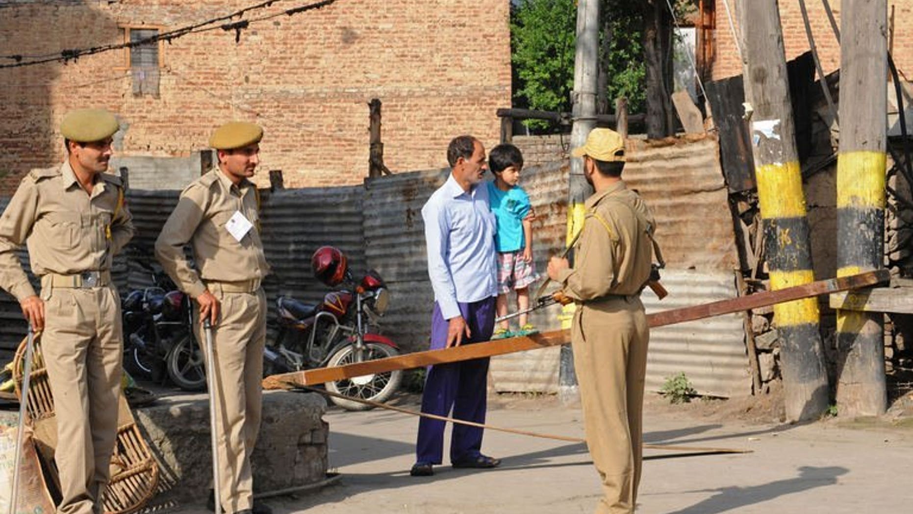 File picture shows a Kashmiri man and his child talking to Indian police during a strike called by separatists in Srinagar, Indian Kashmir on July 13, 2013. Suspected rebels killed a prisoner and wounded four police officers and a passer-by in Indian Kashmir when they lobbed a grenade at a police vehicle Wednesday, police said.