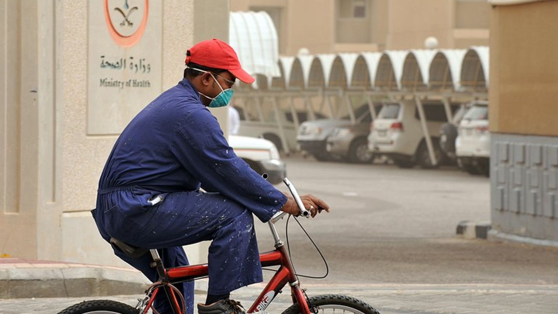 A man wears a mask as he rides a bicycle near the King Fahad hospital in the city of Hofuf, Saudi Arabia on June 16, 2013. The World Health Organization on Wednesday held off from calling for travel restrictions related to the MERS virus striking hardest in Saudi Arabia, after emergency talks on the mystery illness.