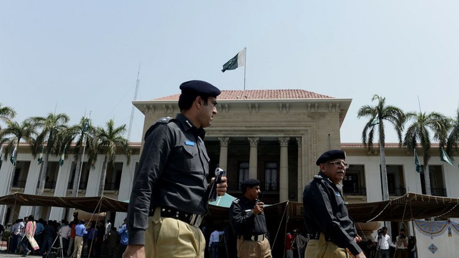 Pakistani police officers walk past Punjab provincial assembly building in Lahore on June 1, 2013. Police in Pakistan have arrested a cook on suspicion of murder after 22 members of a powerful landowning clan were poisoned in an alleged political feud with a rival branch of the family.