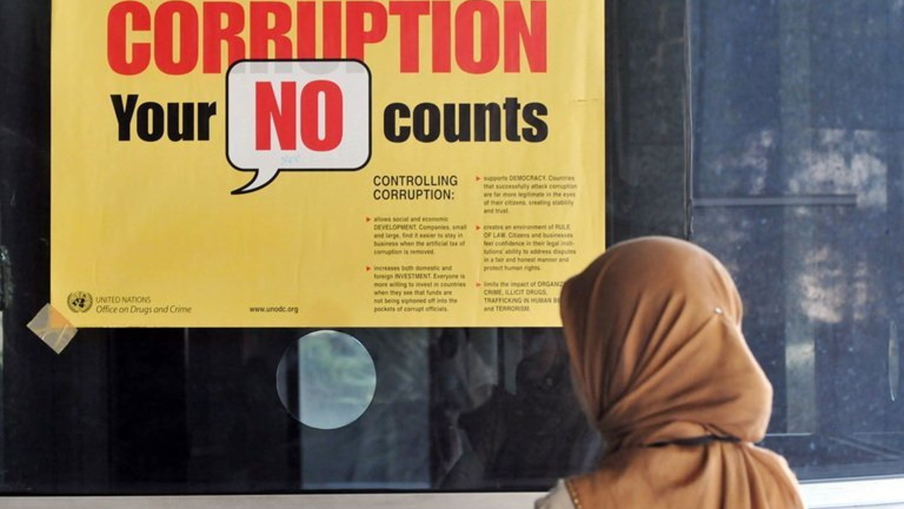 A woman stands next to an anti-corruption campaign banner at a corruption court in Jakarta on July 1, 2009. An Indonesian anti-corruption court Thursday jailed a second employee of the local subsidiary of US energy giant Chevron Corporation, in a case that has alarmed foreign investors.