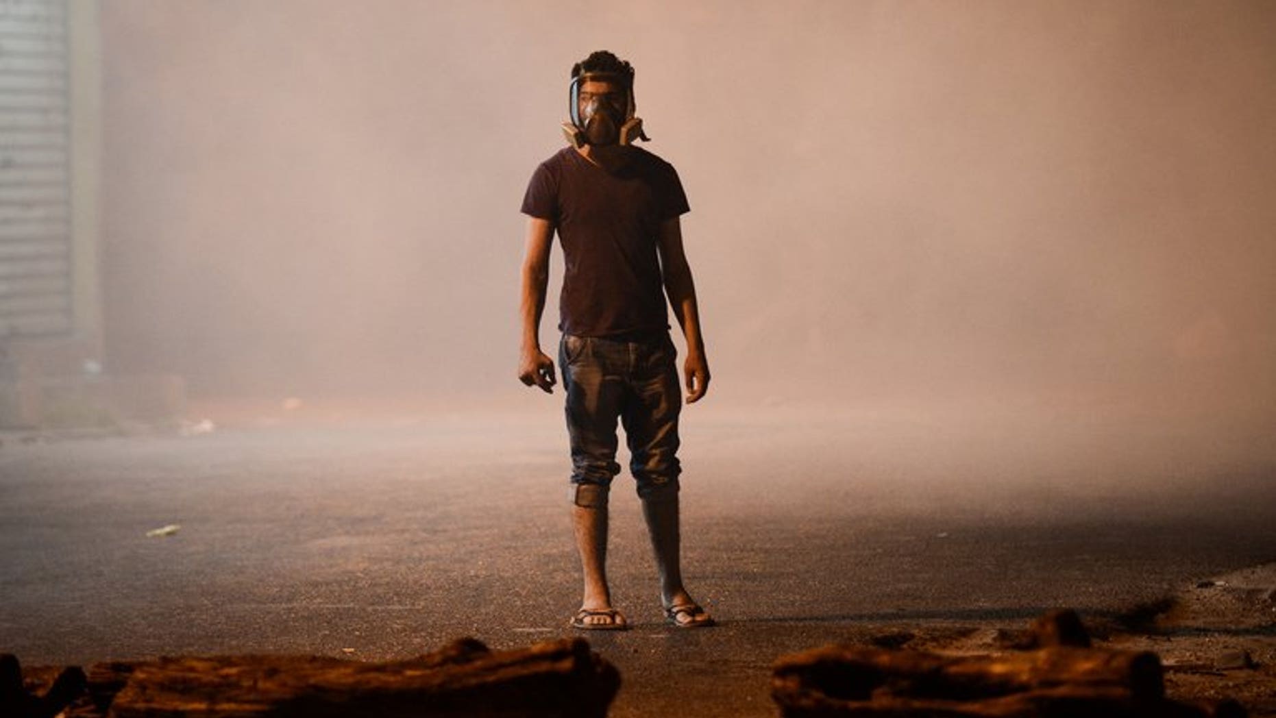 A Bahraini protester wearing a gas mask stands amid tear gas fired by riot police during clashes in the village of Diraz, west of Manama, in the early hours of July 19, 2013. Bahraini security forces clashed with anti-regime protesters early Friday, leaving several people wounded including a policeman who was shot with a home-made gun, the interior ministry and witnesses said.