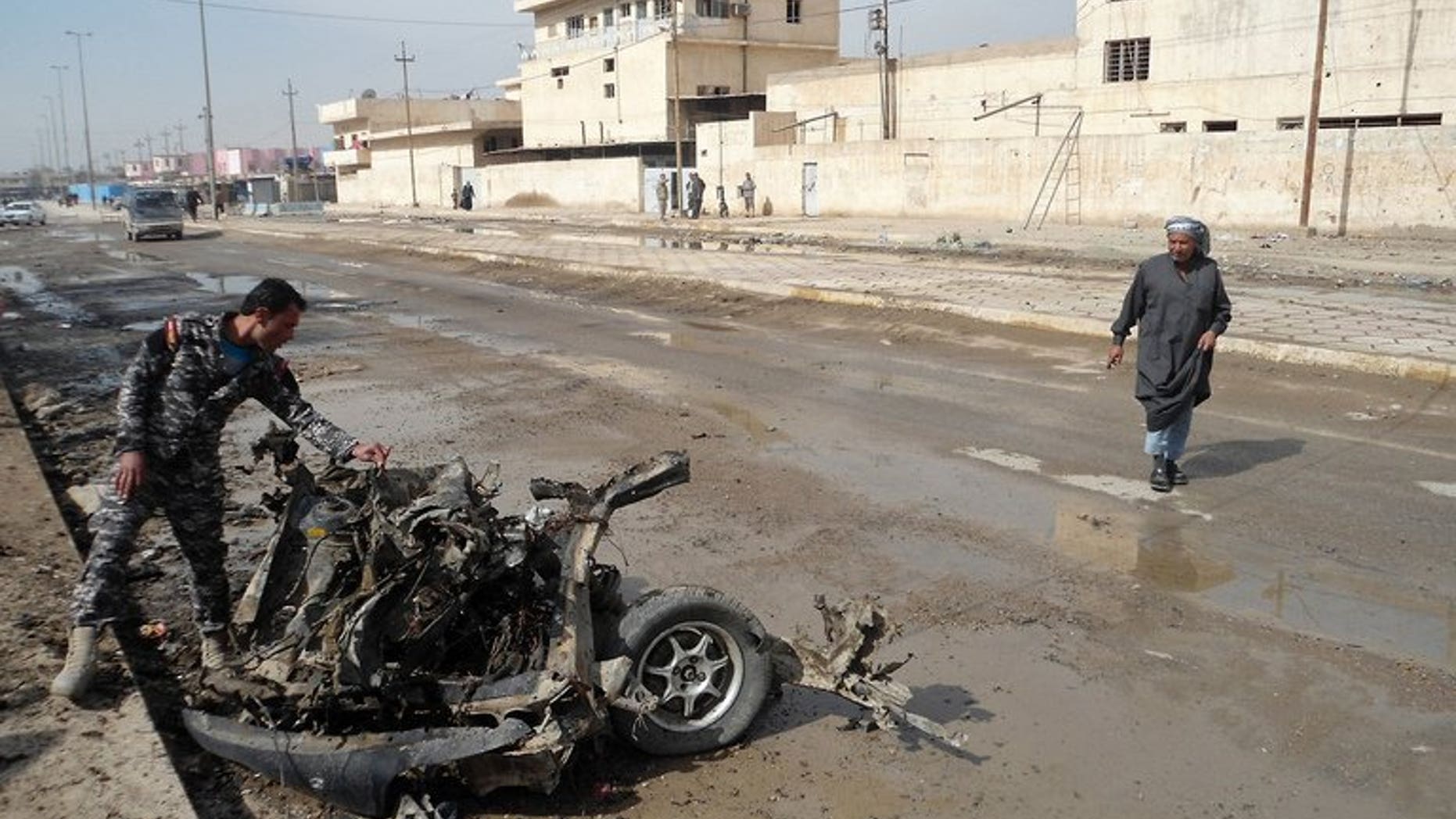 An Iraqi policeman inspects the debris of a vehicle following a blast in Baquba, capital of Diyala province, on February 23, 2012. A bomb exploded in a crowded mosque north of Baghdad on Friday afternoon, killing at least 20 people and wounding 40, police said.