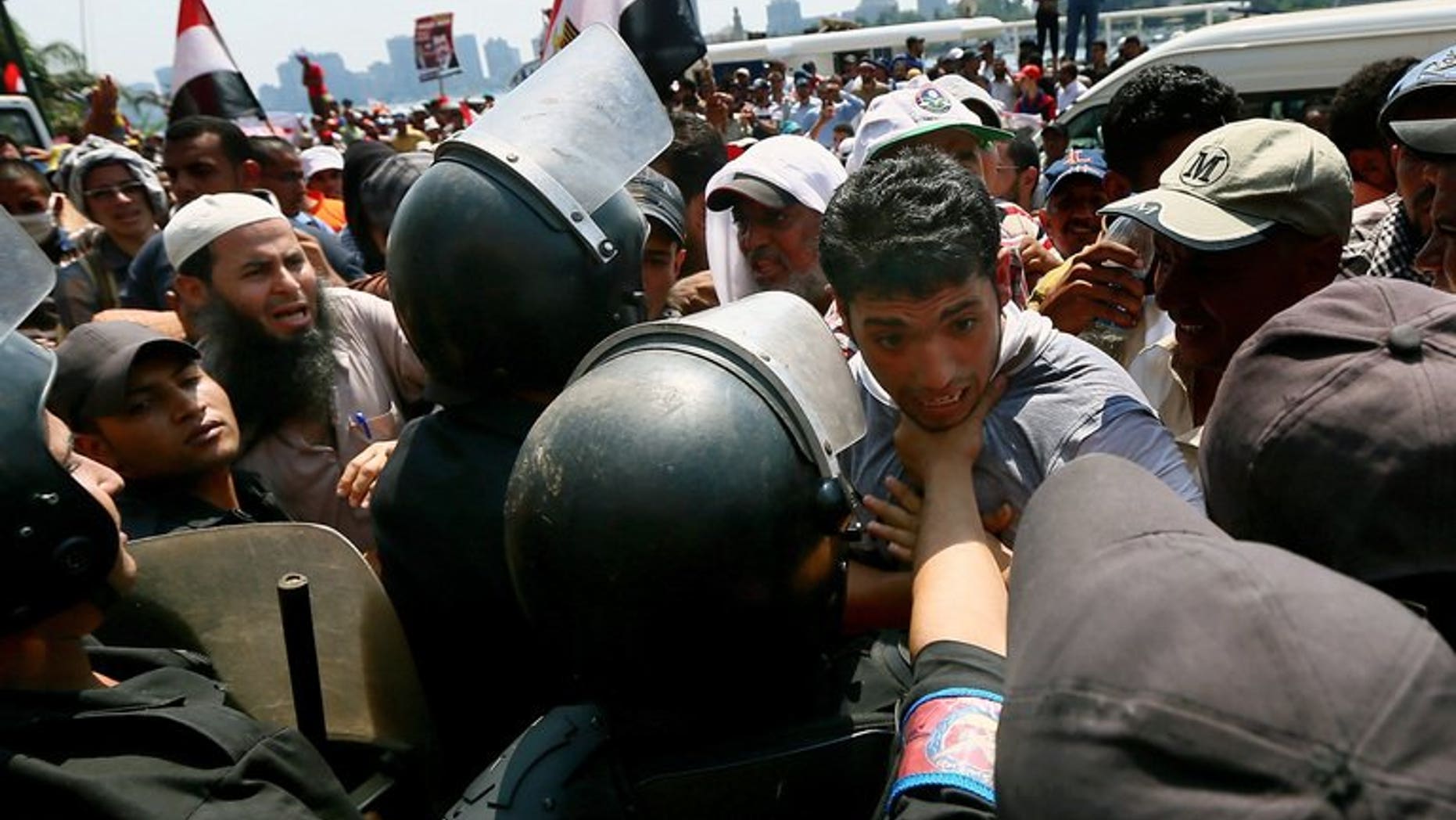 A supporter of Egypt's ousted president Mohamed Morsi is held back by riot police during a rally in Cairo on July 17, 2013. Britain has announced it is revoking export licences for equipment used by Egypt's military and police amid concerns it could be used against protesters.
