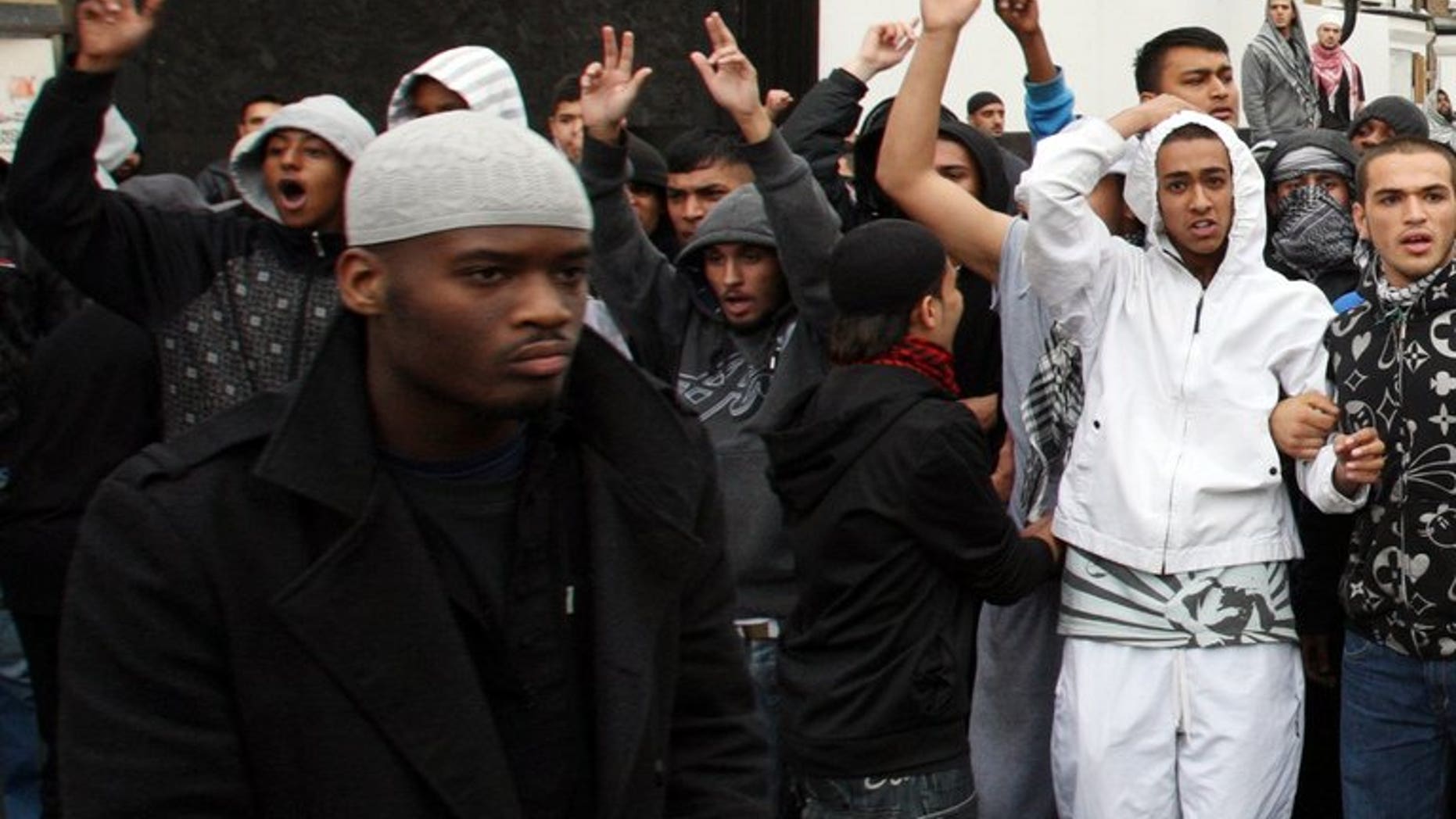 Michael Adebolajo (left) walks by a line of people near Harrow Mosque in London on September 11, 2009. Five staff at a London jail have been suspended after Adebolajo, one of the men accused of murdering a British soldier, reportedly lost two teeth while being restrained, officials said