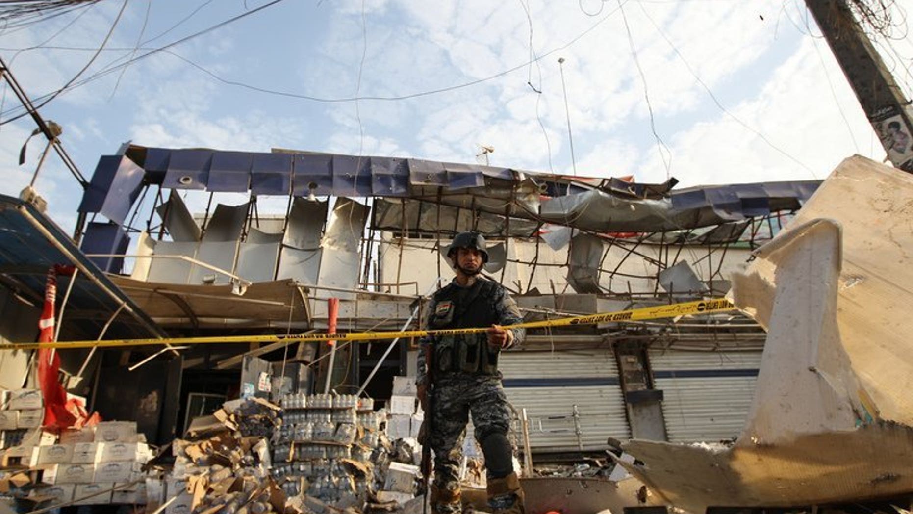 An Iraqi policeman inspects the damage outside a supermarket in central Baghdad's commercial Karrada neighbourhood on June 25, 2013. At least 22 people were killed in a string of car bomb attacks on Saturday timed for nightfall when shoppers take to the streets during Ramadan, security and medics said.