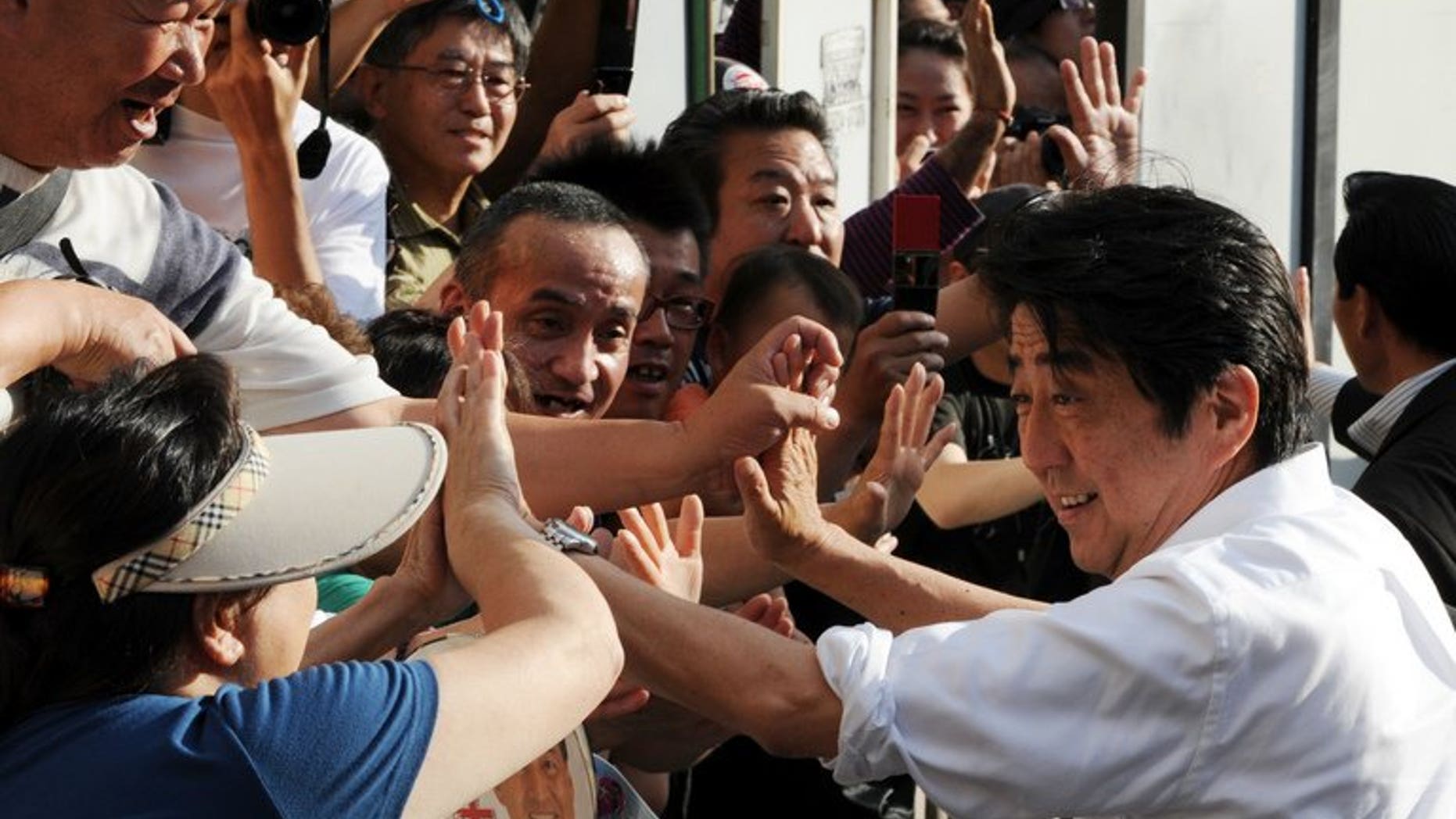 Japanese Prime Minister and ruling Liberal Democratic Party leader Shinzo Abe (R) greets supporters in Tokyo on July 20, 2013. Japanese voters go to the polls Sunday in an election expected to strengthen Abe's hand, potentially giving him power to push much-needed economic reforms.