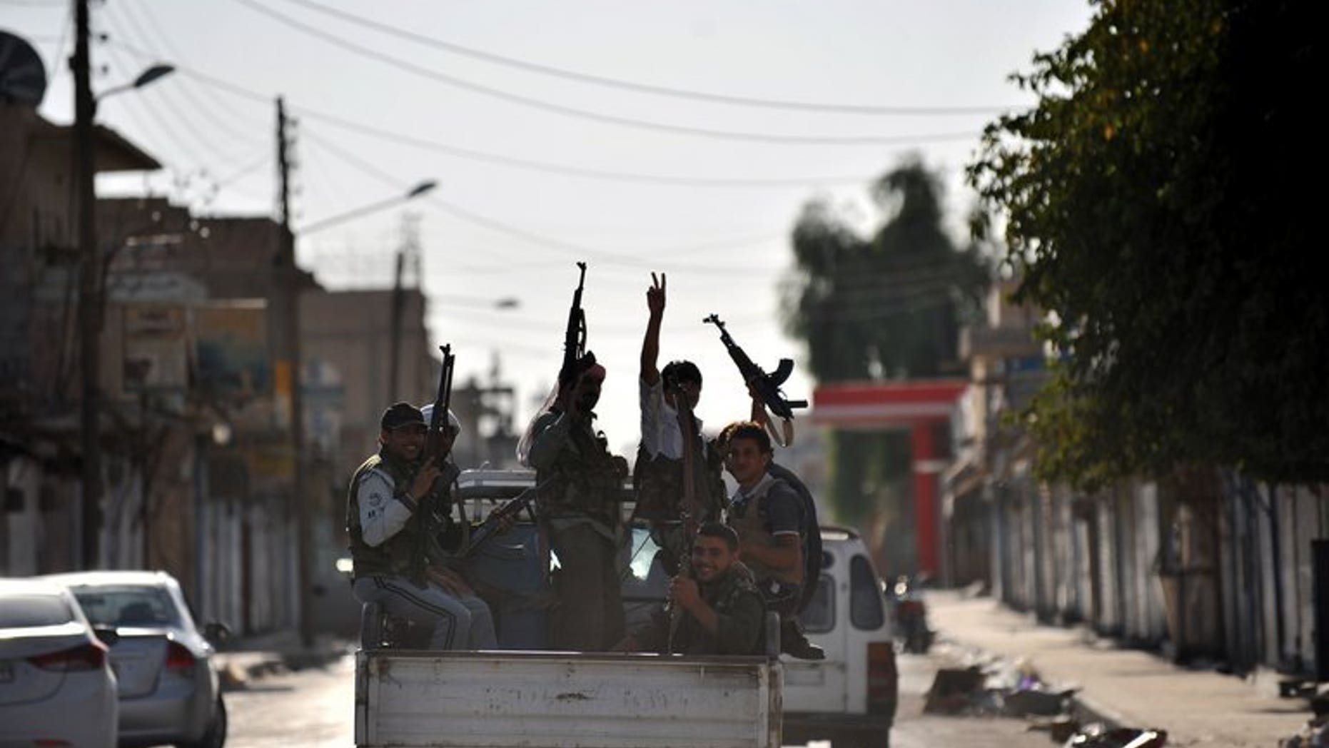 Syrian rebels raise their weapons during a patrol in the town of Tal Abyad near the border with Turkey on October 5, 2012. Syrian Kurdish fighters in the north fought fierce battles against jihadists and captured a commander of the Islamic State of Iraq and the Levant (ISIS) late Saturday, a monitoring group said.