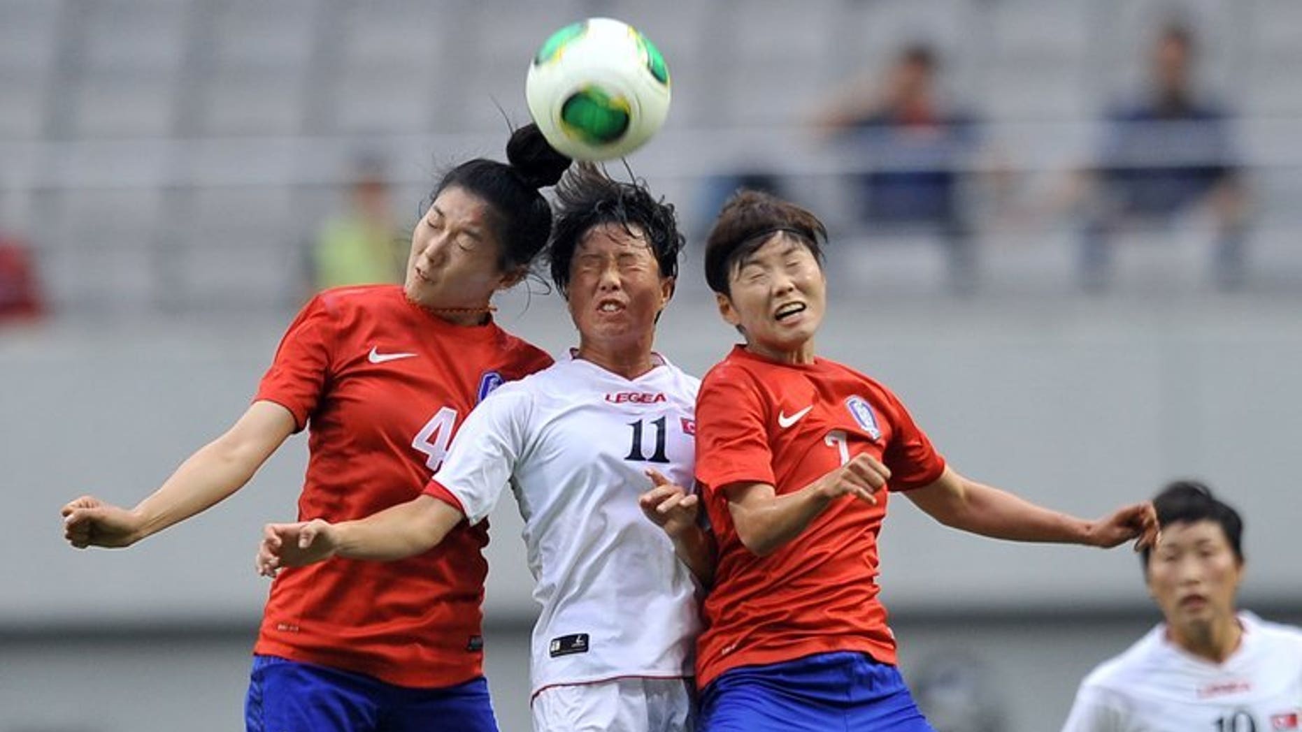 North Korea's Ri Ye-Gyong (centre) competes with South Korea's Shim Seo-Yeon (left) and Jeon Ga-Eul (right) during the Women's East Asian Cup football match in Seoul on July 21, 2013. North Korea won the match 2-1.