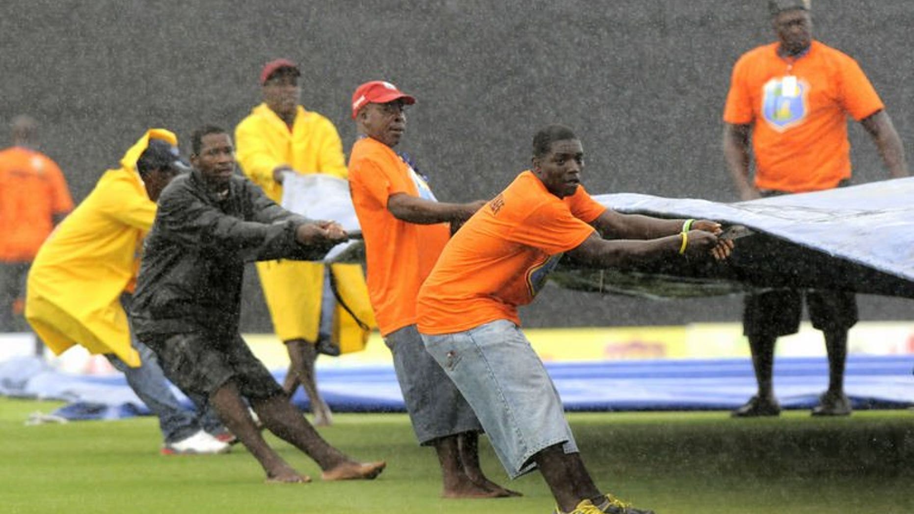Ground staff struggle to pull covers in place at the start of the 4th one-day internatioanl between West Indies and Pakistan on July 21, 2013 in Gros Islet, St. Lucia.
