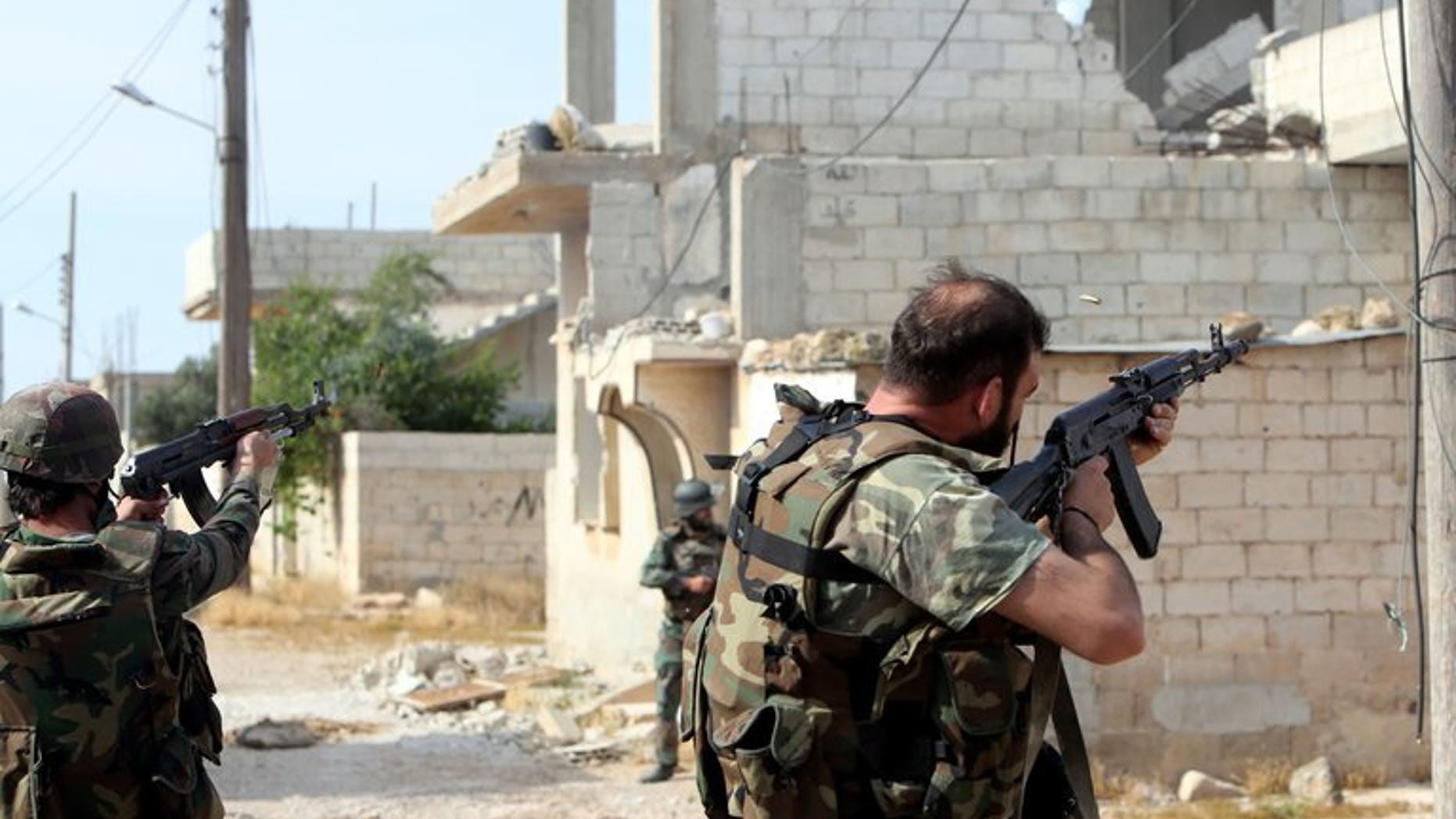 Syrian soldiers fire their weapons during a battle against opposition fighters in Qusayr, on May 23, 2013. A Syrian pro-regime militia shot dead 13 members of the same family, including six children, in the Mediterranean coastal village of Bayda, according to the Syrian Observatory for Human Rights.