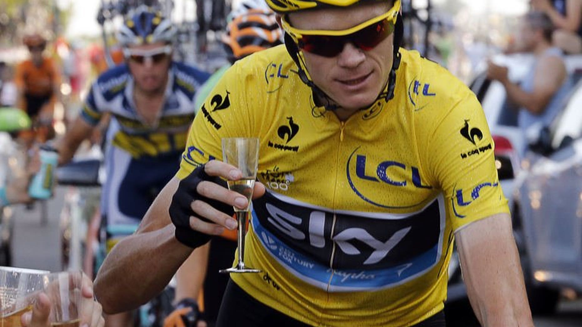 Overall leader's yellow jersey Britain's Chris Froome holds a glass of Champagne as he rides next to his team car, during the 133.5 km twenty-first and last stage of the 100th edition of the Tour de France cycling race on July 21, 2013 between Versailles and Paris. Froome was crowned champion of the 100th edition of the Tour de France.