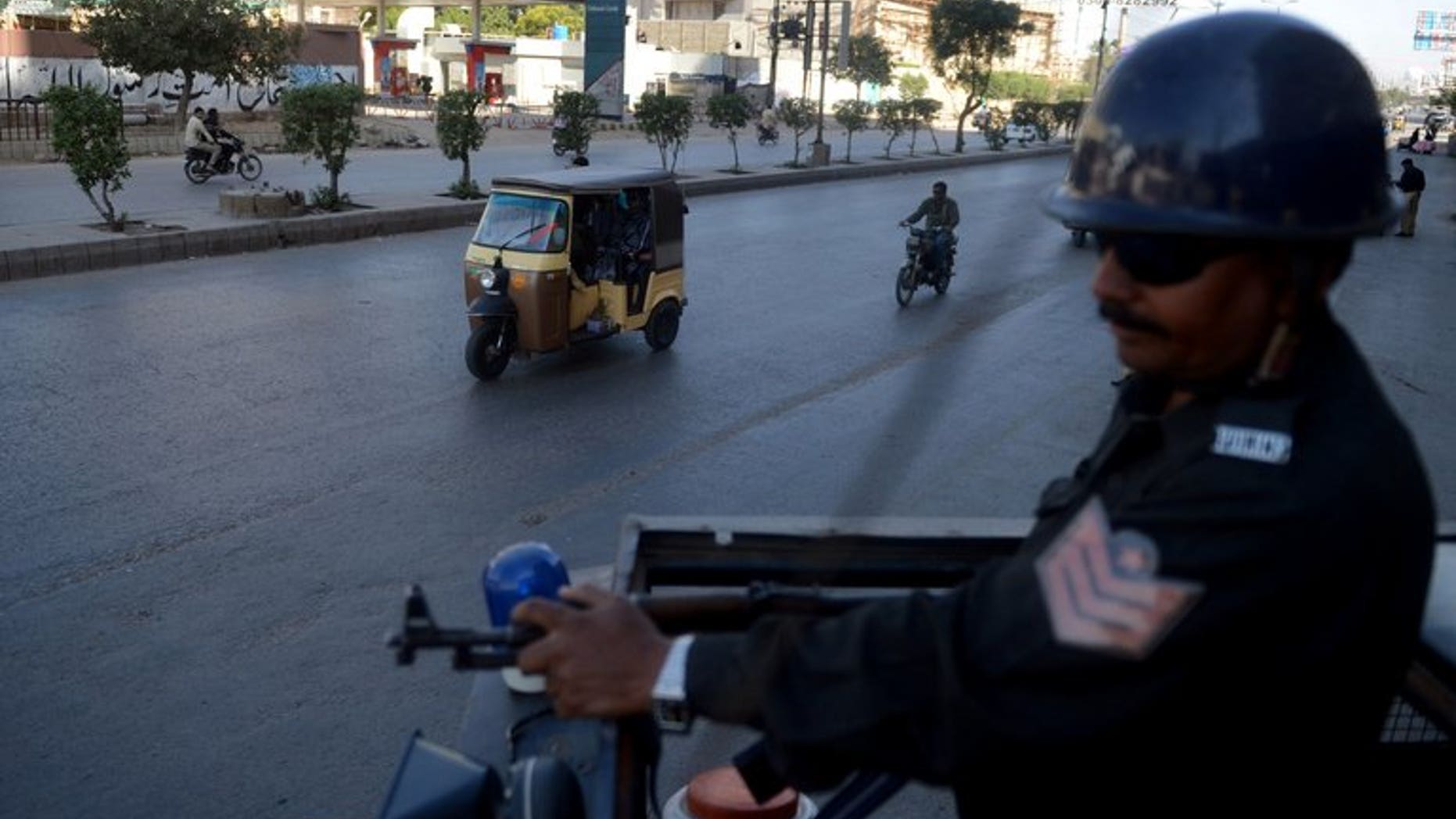 A Pakistani policeman stands guard on a police van in Karachi on February 8, 2013. A hand grenade attack targeting the office of a political party late Sunday killed at least two people and wounded six others in Pakistan's port city of Karachi, police said.