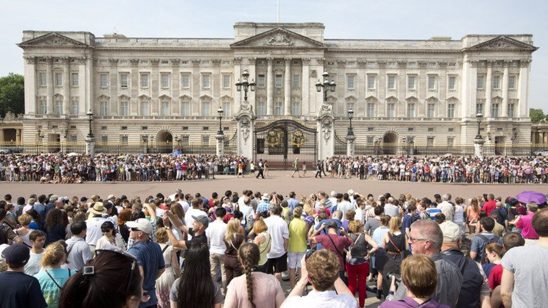 Crowds of tourists gather on the steps of the Queen Victoria Memorial Statue outside Buckingham Palace in central London on July 22, 2013.
