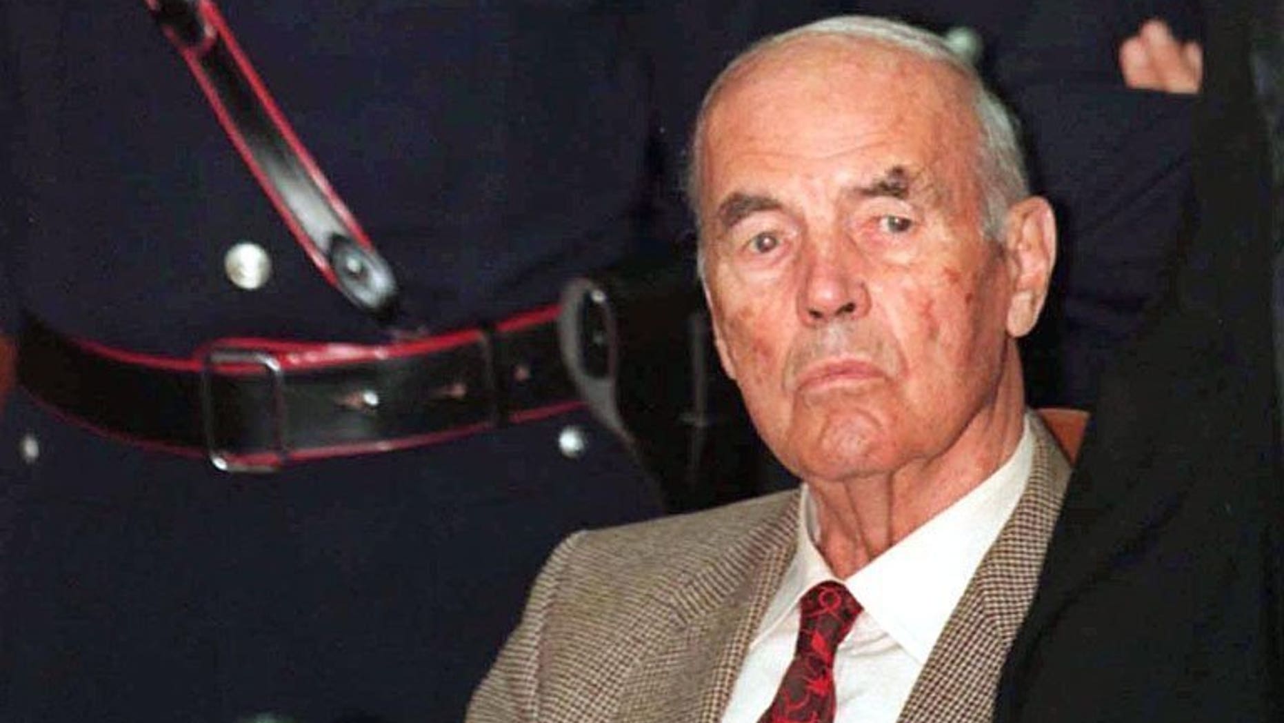 This file picture taken on July 30, 1996 shows former German SS officer Erich Priebke surrounded by police at a military court in Rome. The 100th birthday of Priebke -- one of the last Nazi criminals alive -- has sparked calls for a public apology from relatives of his victims 69 years after their murder and resentment over his freedom of movement.