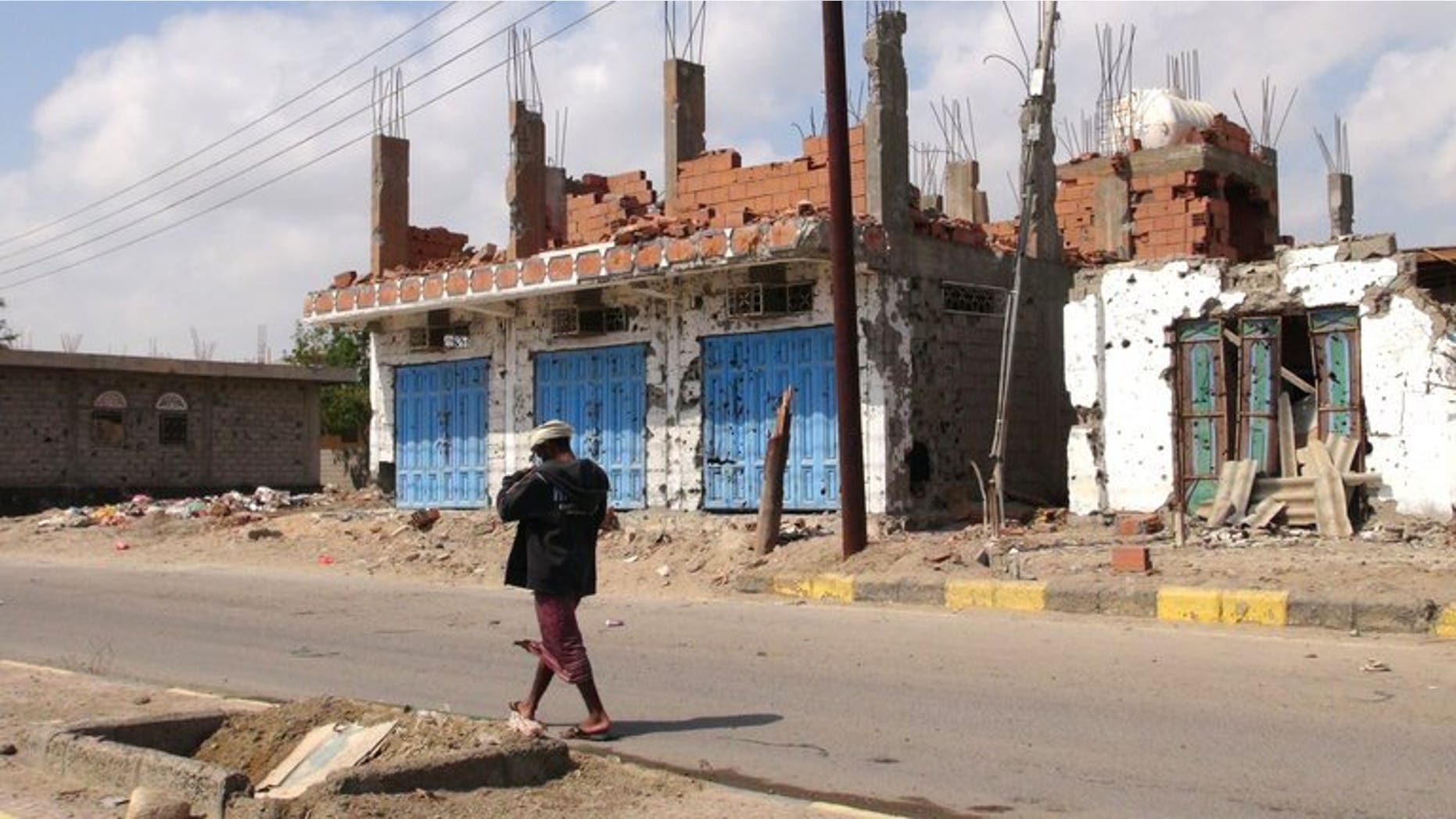 A Yemeni man walks past destroyed buildings in Zinjibar, capital of Abyan province in southern Yemen on December 5, 2012. Yemeni authorities have released a journalist who had been detained for three years on charges of promoting Al-Qaeda, the state news agency Saba reports.