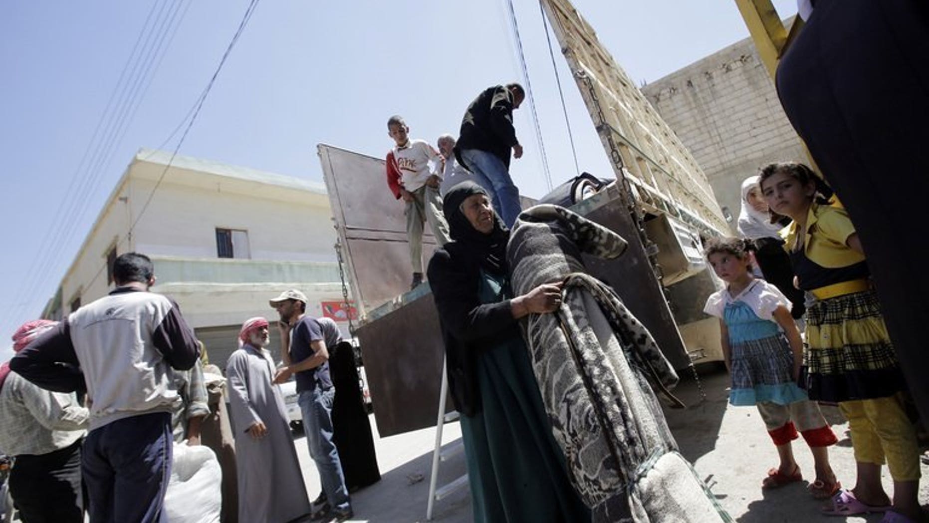 A Syrian woman carries her belongings upon her arrival in the Bekaa valley where she will find shelter, on June 14, 2013. The Lebanese government has imposed new entry controls on Syrians in a bid to reduce friction between the host population and the 600,000 who have already crossed.