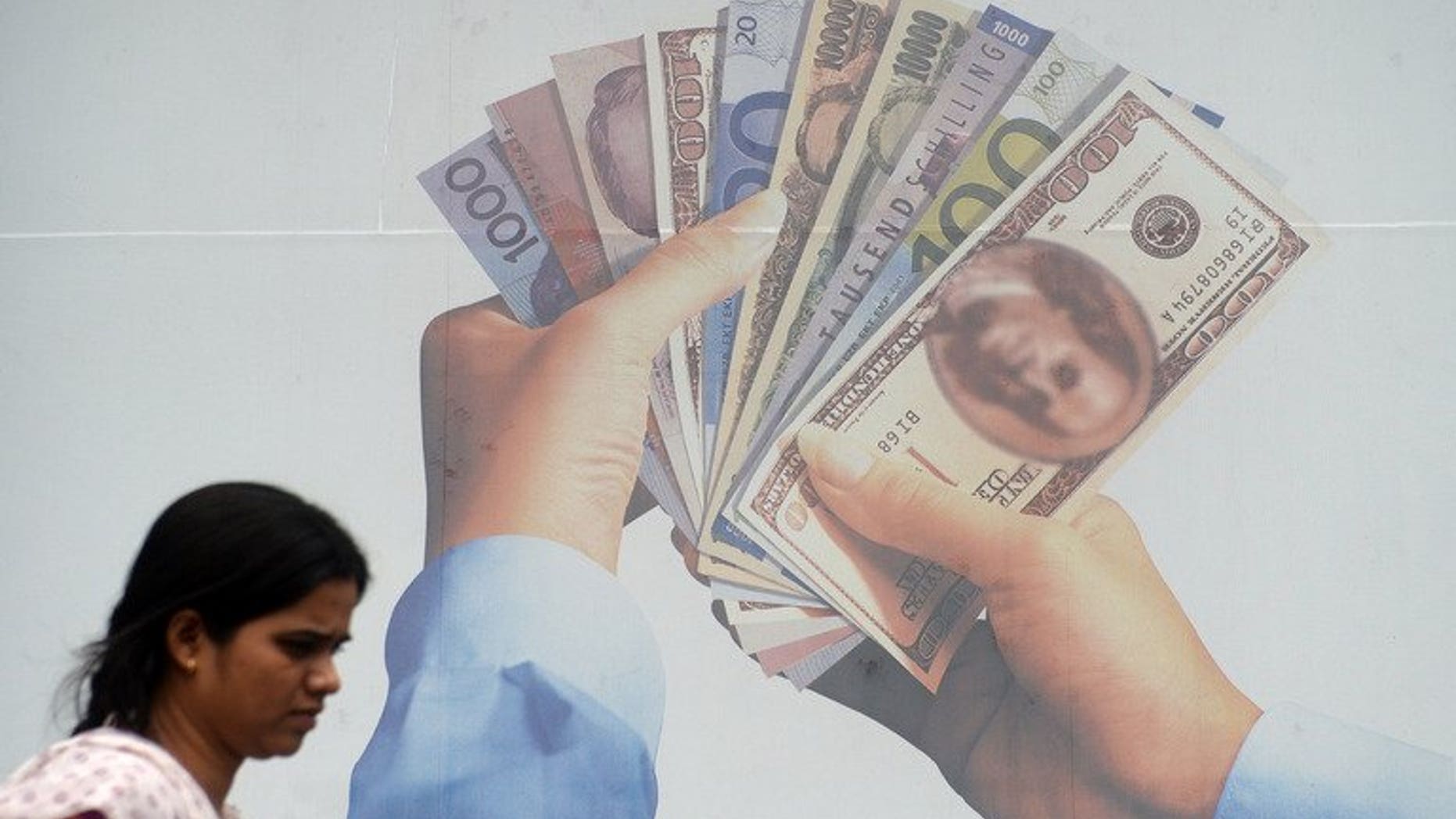 An Indian pedestrian walks past a foreign exchange advertising billboard in Mumbai on June 20, 2013. India's rupee strengthened against the dollar on Wednesday after the central bank took new measures to support the ailing currency.