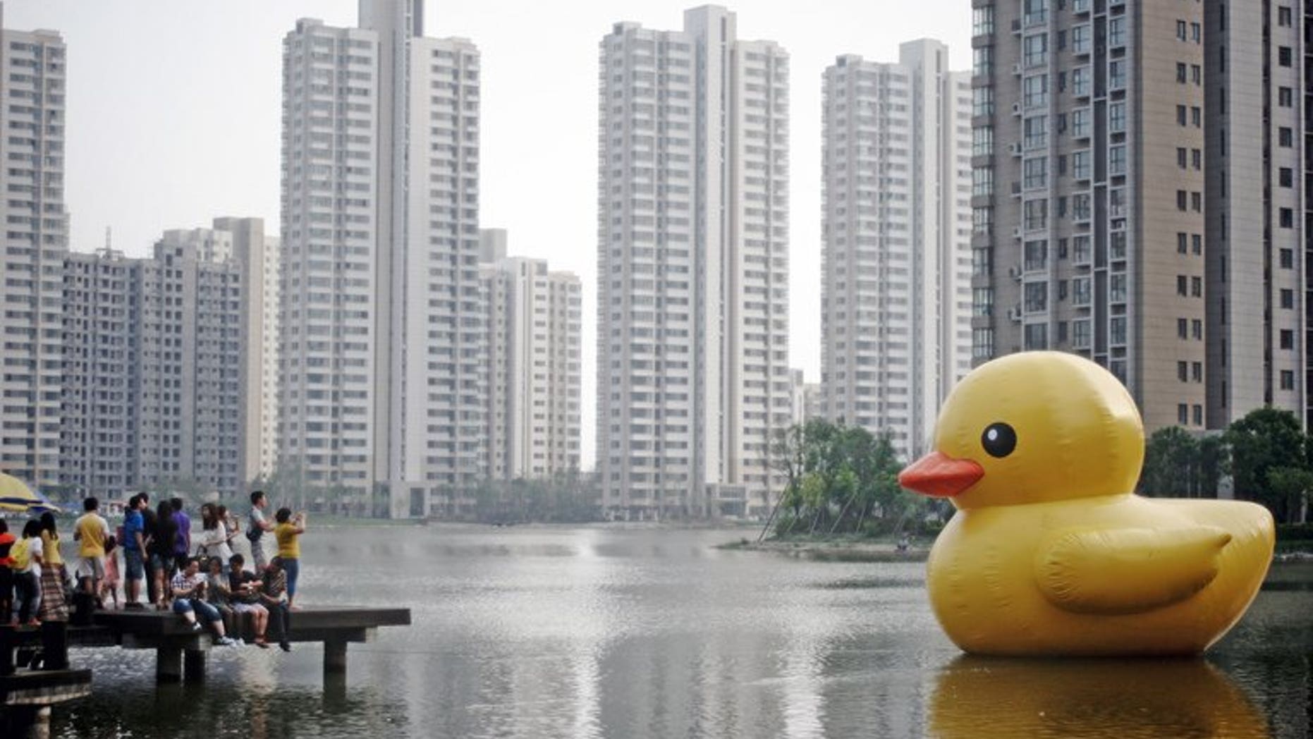 This picture taken on June 1, 2013 shows visitors taking photos of a giant inflatable duck in eastern China's Tianjin. The popularity of a giant inflatable duck afloat in Hong Kong harbour has not gone unnoticed in mainland China, where two copies have been launched in as many days, according to reports on June 1. CHINA OUT AFP PHOTO
