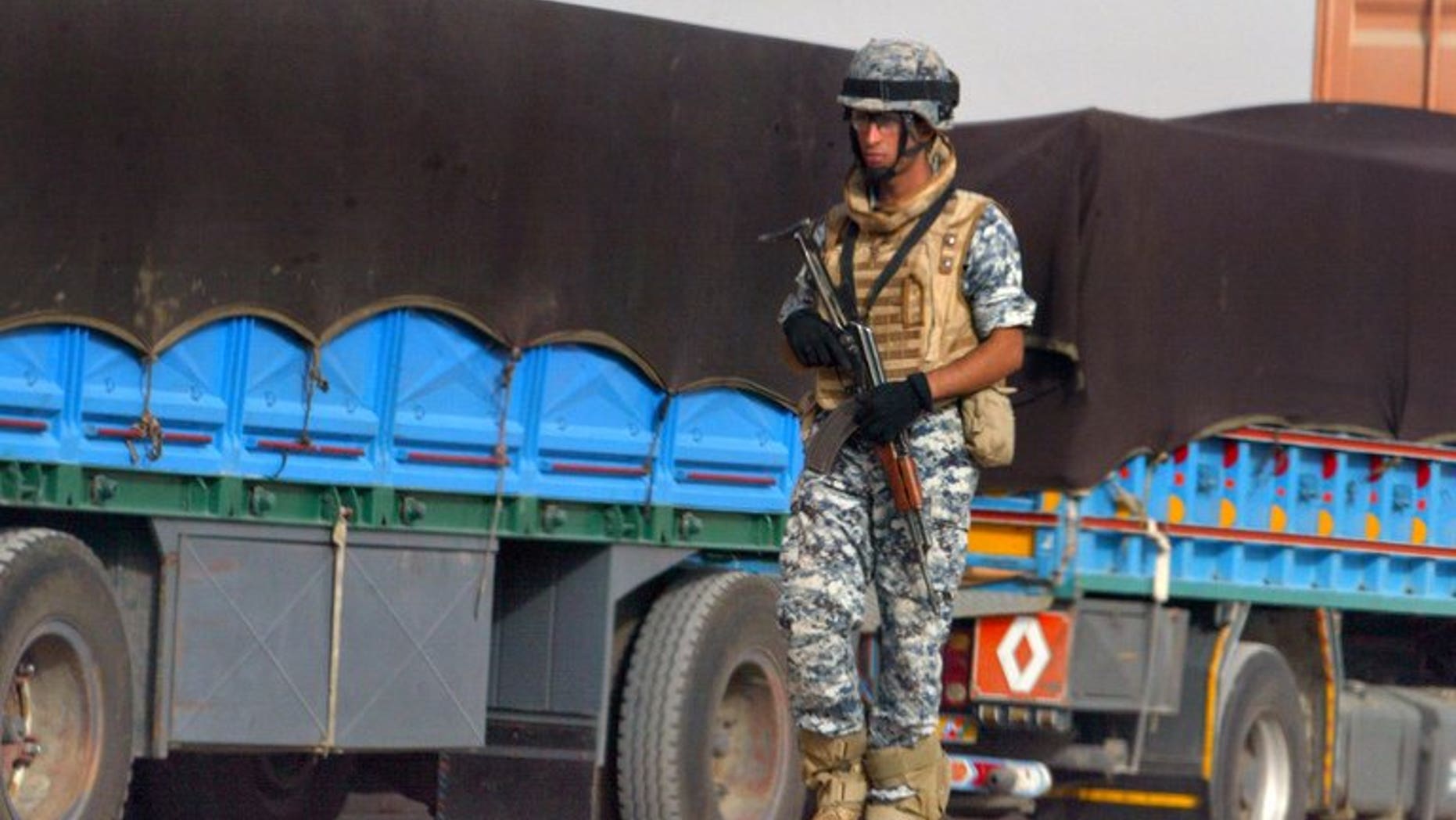 An Iraqi policeman walks past trucks in Amara on June 20, 2008. Gunmen killed 14 truck drivers and stole their vehicles on a highway north of Baghdad on Thursday, while dozens of other militants attacked a nearby town, a local administrative official said.