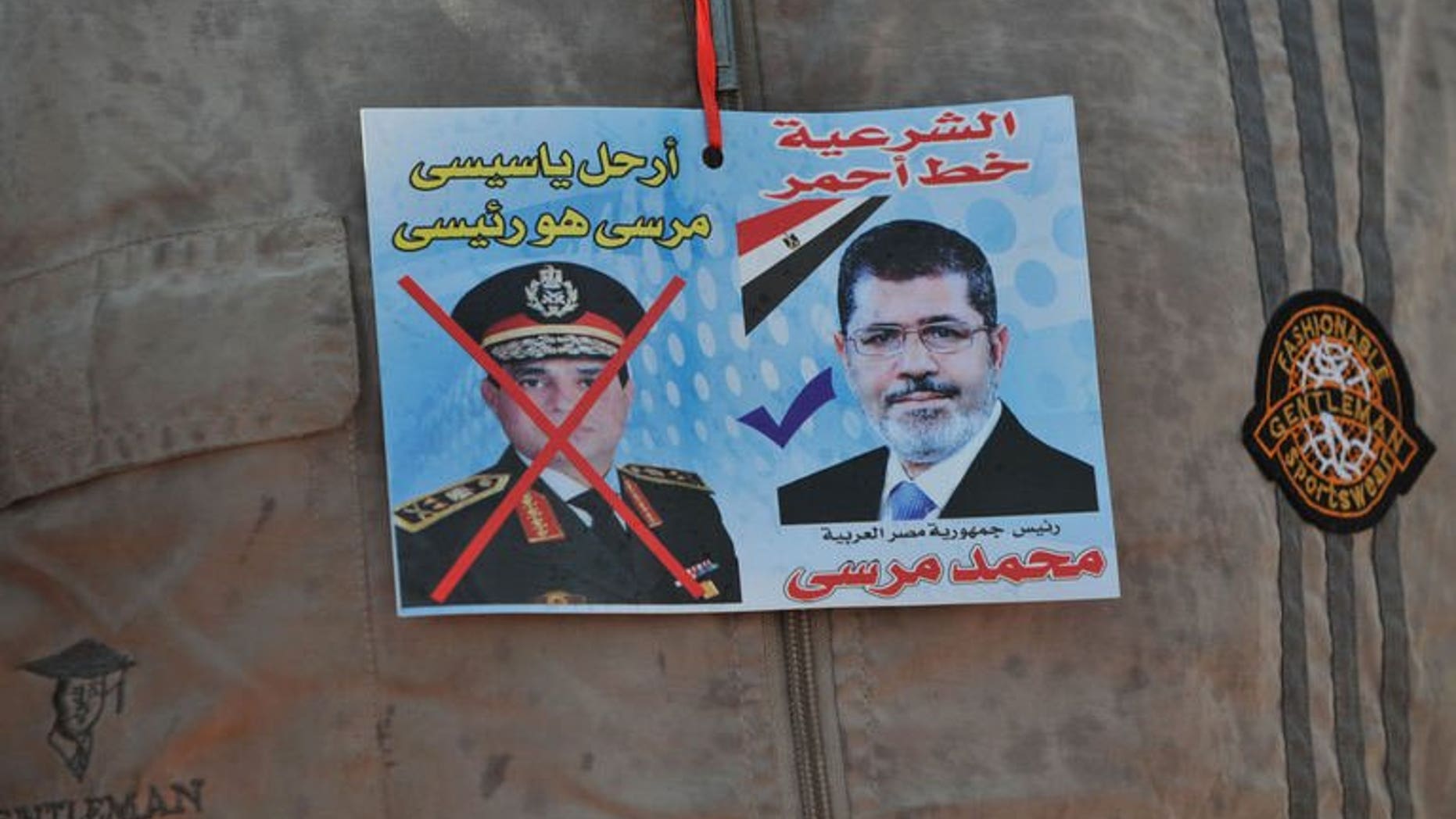 A sticker on the shirt of a supporter of Egypt's ousted president Mohamed Morsi shows Morsi (R) with text above it reading in Arabic: "Legitimacy is the red line" and one of army chief Abdel Fattah al-Sisi (L) with text above reading in Arabic: "Leave Sisi, Morsi is the president" outside Cairo's Rabaa al-Adawiya mosque on July 24, 2013.