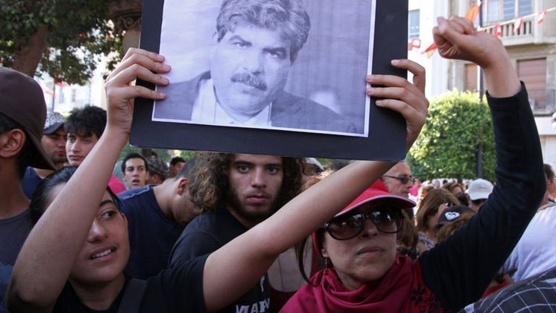 Tunisians hold a portrait of slain opposition politician Mohamed Brahmi on July 25, 2013. Tunisian Interior Minister Lotfi Ben Jeddou has said that Brahmi was killed with the same weapon as fellow opposition figure Chokri Belaid.