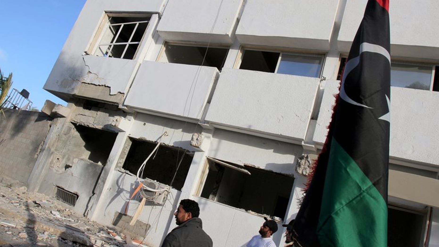 Libyan security forces and bystanders walk outside a damaged police station on April 27, 2013 in Benghazi. A marksman shot dead a prominent Libyan political activist as he emerged from Friday prayers at a mosque in the restive eastern city of Benghazi, a security official said.