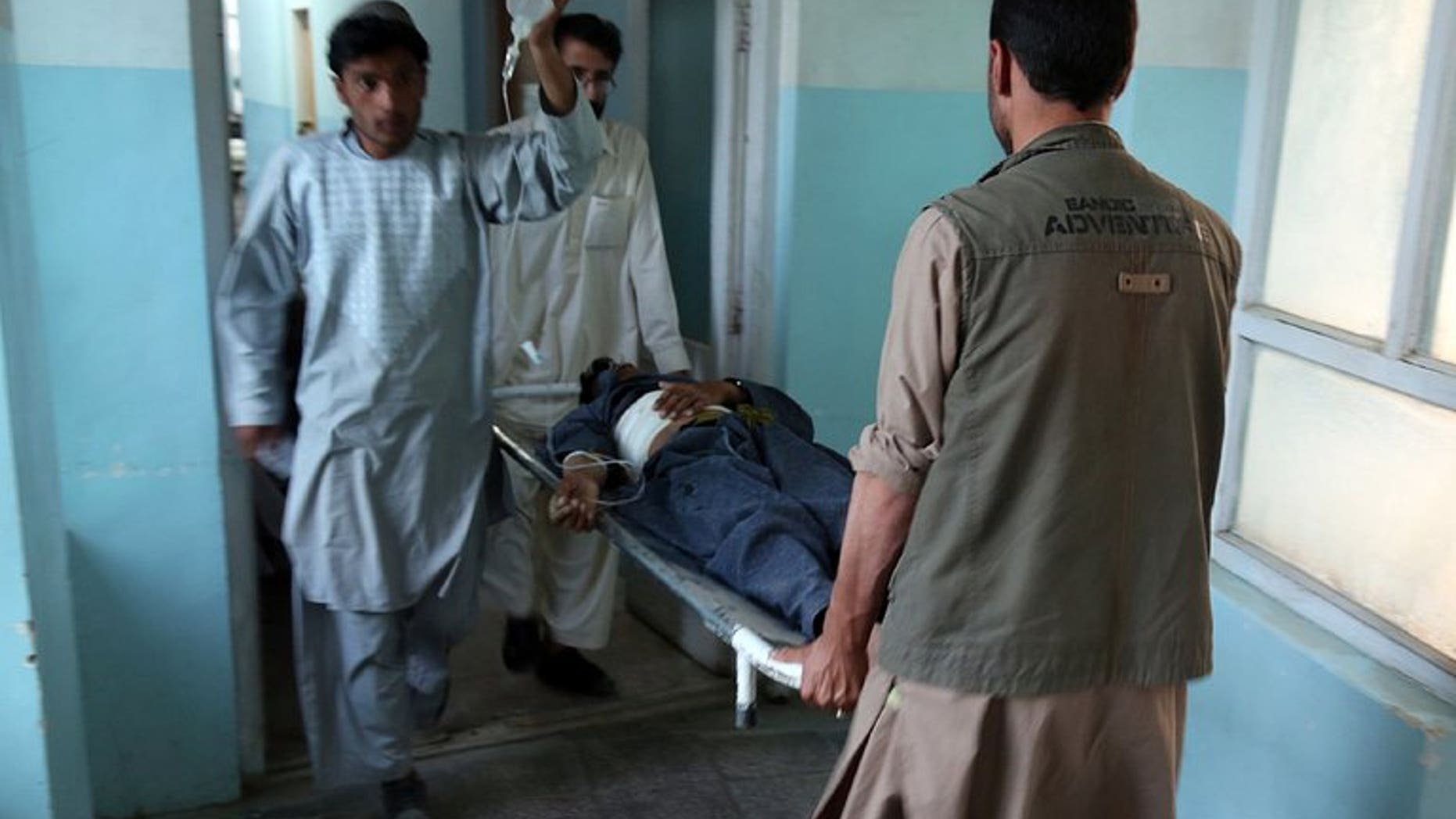 Medical staff carry a wounded man at the main hospital in Ghazni after a suicide attack in Qara Bagh district, on July 26, 2013. A suicide bomber riding a motorcycle struck a busy marketplace and killed seven people, including an anti-Taliban militia leader.