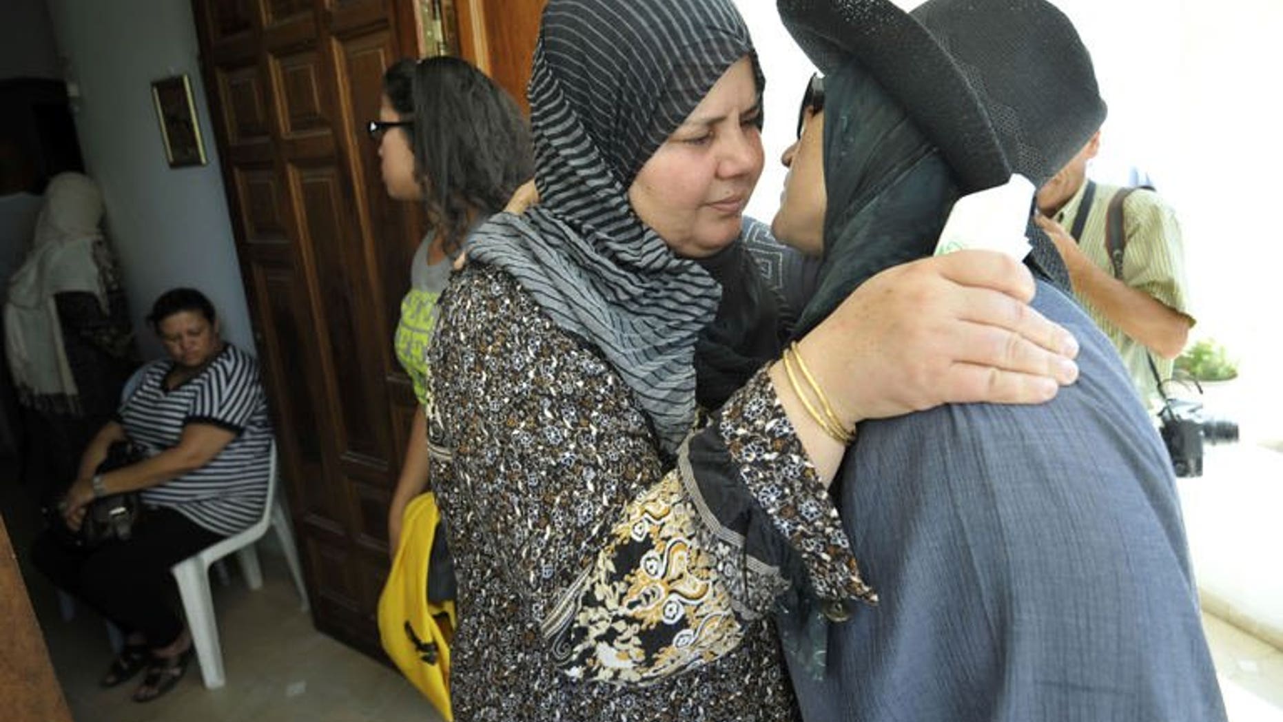 Mubarka Brahmi (centre), the wife of slain opposition politician Mohamed Brahmi, receives condolences from Tunisians at her house in Ariana,Tunisia on July 25, 2013. The politician's funeral procession left his home under military escort on Saturday.