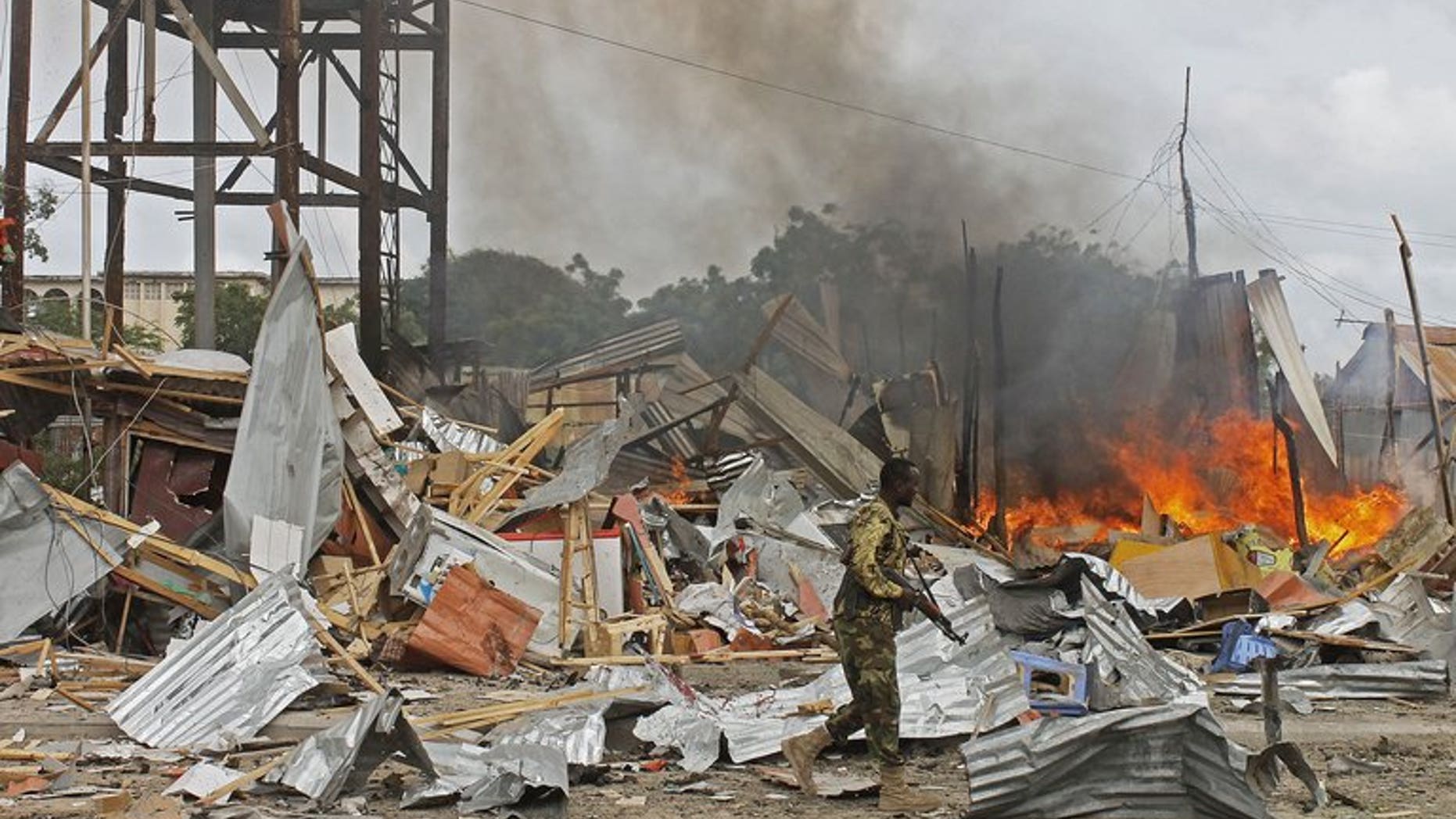A Somali National Government (SNG) soldier walks past burning debris after a suspected suicide bomber rammed a car laden with explosives into an armoured convoy of African Union troops in Mogadishu on July 12, 2013. A suicide car bomb attack struck a Turkish embassy building in Mogadishu Saturday, killing one Somali civilian and wounding two Turkish policemen, a diplomat and a witness said.
