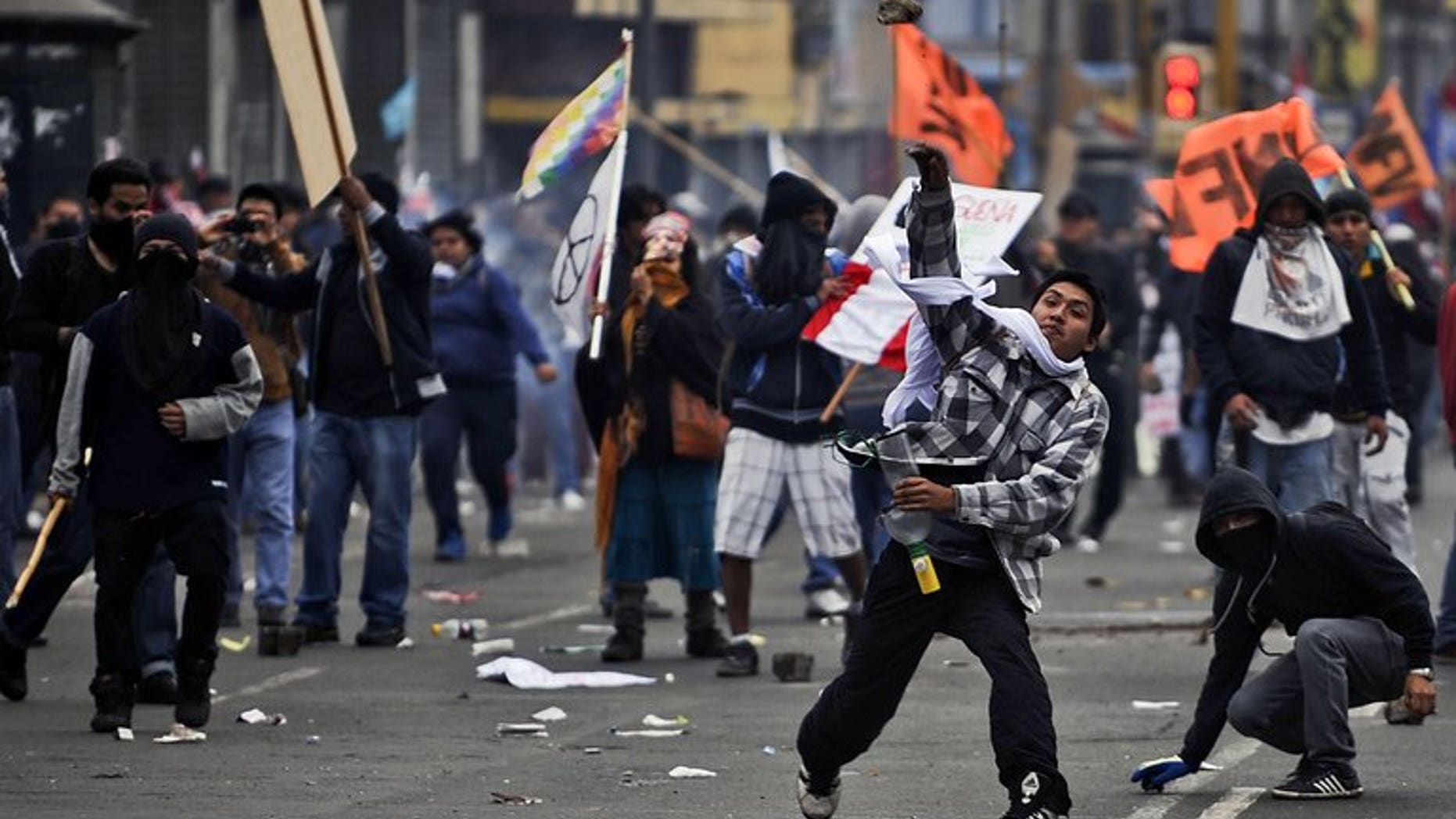 Demonstrators throw stones at riot police in Lima on July 27, 2013. Peruvian police used tear gas and water cannon to drive back thousands of demonstrators protesting against what they said were President Ollanta Humala's failed promises on schools and jobs.