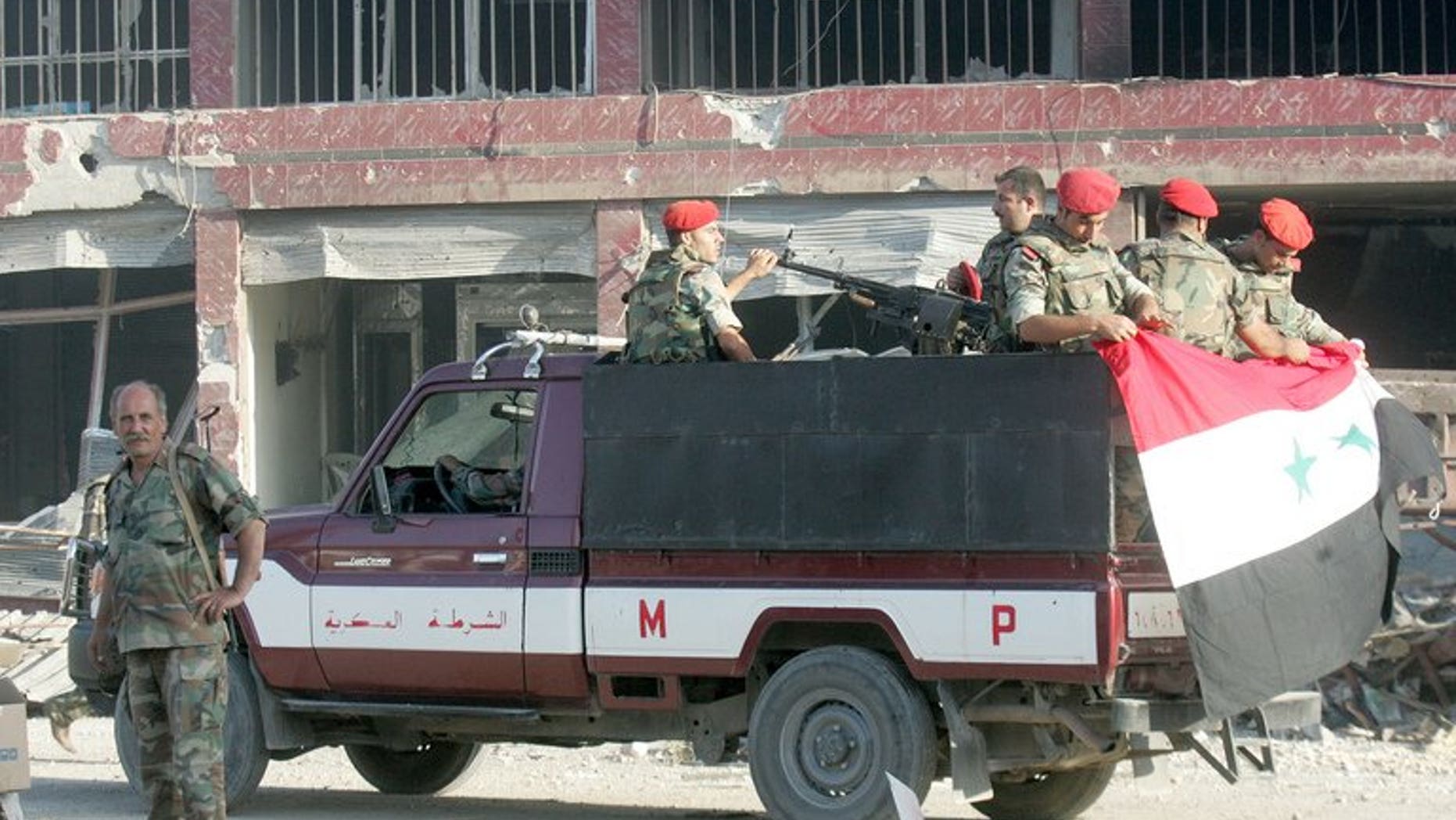 Syrian army troops patrol a ruined street in Qusayr in Homs province. The opposition Syrian National Coalition on Sunday condemned the reported "collective execution" by rebels of soldier prisoners in the north and said it had created a commission of inquiry.