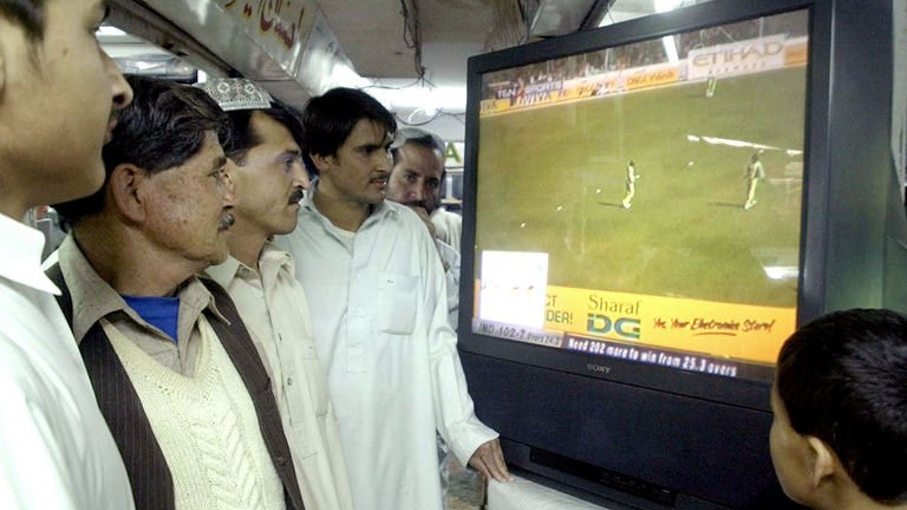 Pakistani men watch a television screen broadcasting a match between India and Pakistan in New Delhi at a shop in Quetta on April 17, 2005. Muneer Hussain, Pakistan's most famous cricket voice and a man credited with pioneering Urdu language commentary, has died after a prolonged illness.