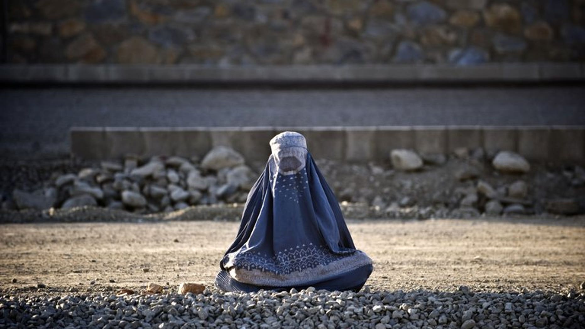 A burqa-clad woman sits on the roadside in Kabul on August 19, 2009. The fate of Afghanistan's women hangs in the balance as the 2014 withdrawal of international forces looms, a UN human rights watchdog warned Monday, denouncing a raft of abuses there.