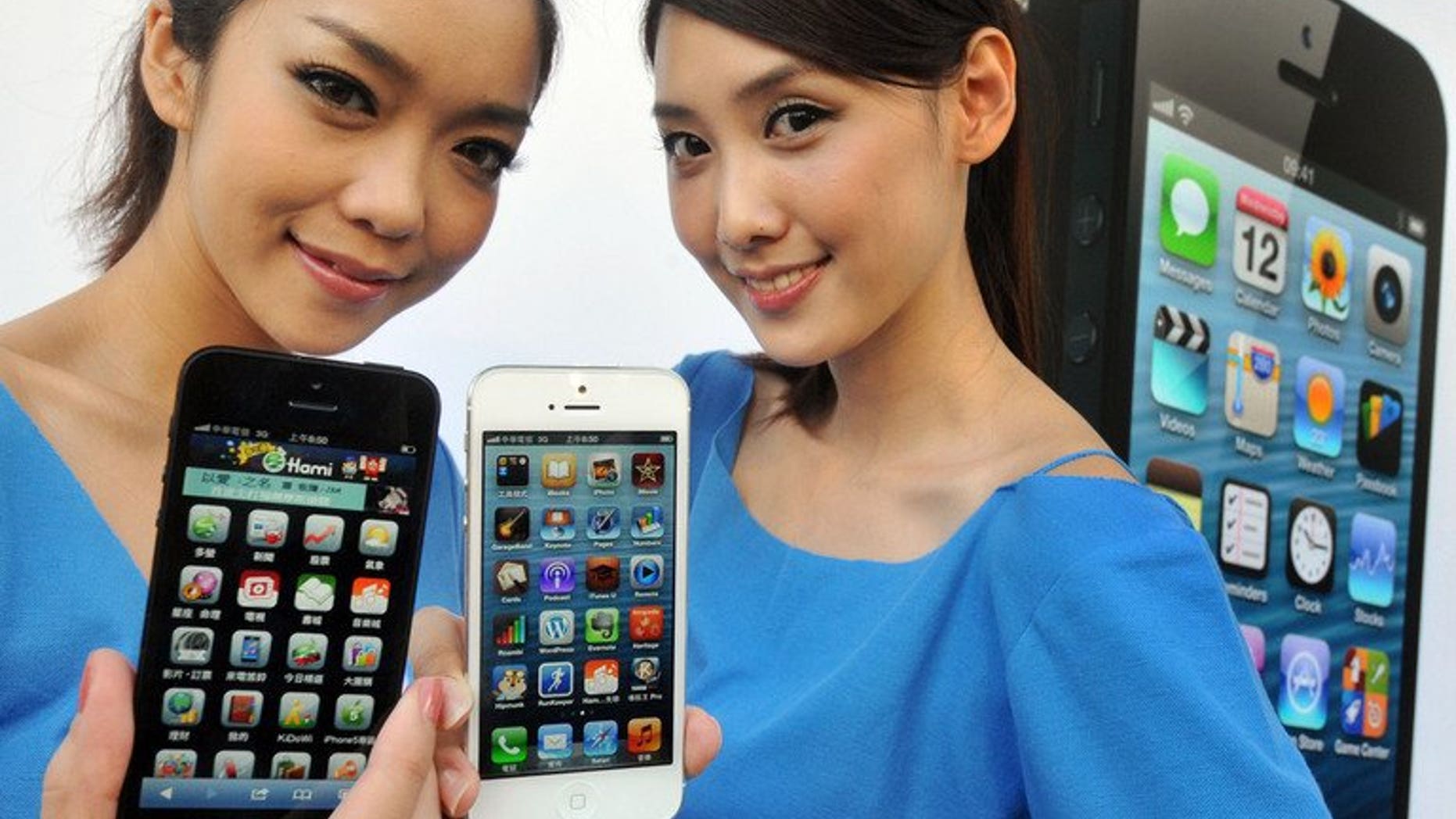 Women hold the Apple iPhone 5 during a launch at a store in Taipei last December. A Taiwanese company which assembles some Apple devices said Tuesday it is investigating claims of labour abuses by a US rights group.
