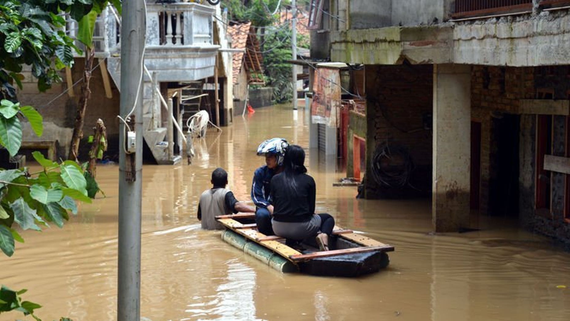 File picture shows residents in an improvised raft travelling down a flooded lane in south Jakarta on March 5, 2013 following heavy rains in nearby mountain areas. At least eight people are dead and five are missing after flooding and landslides hit eastern Indonesia, an official said on Tuesday.
