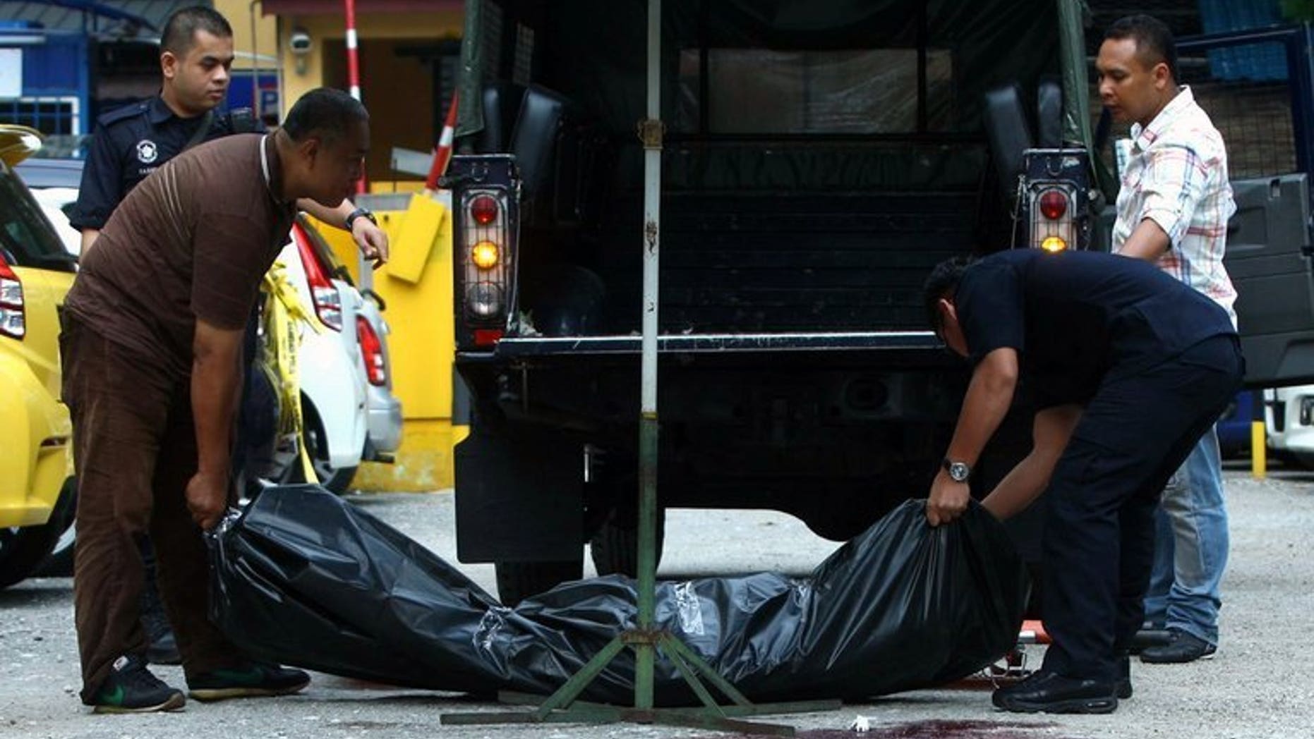 This picture taken on July 29, 2013 shows Malaysian forensic police carrying the body of late Arab Malaysian Banking Group founder Hussain Ahmad Najadi after he was shot dead in a parking lot in Kuala Lumpur. Malaysian police said Tuesday they were hunting suspected contract killers after the bank founder was gunned down in broad daylight.
