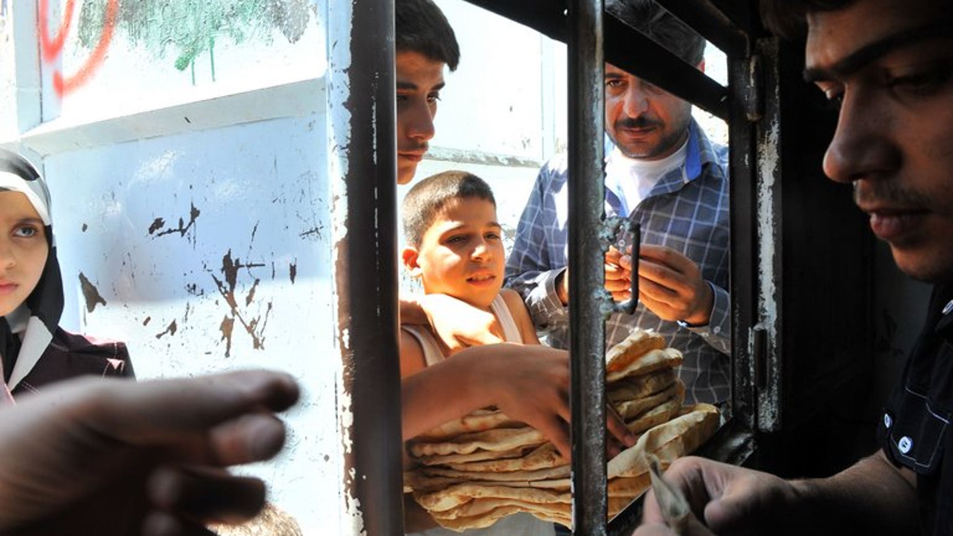 Syrians buy bread at a bakery in the northern city of Aleppo on August 19, 2012, on the first day of the Eid al-Fitr. The Arab League and the Organisation of Islamic Cooperation jointly appealed Tuesday to warring parties in Syria to observe a ceasefire during next week's feast of Eid al-Fitr.