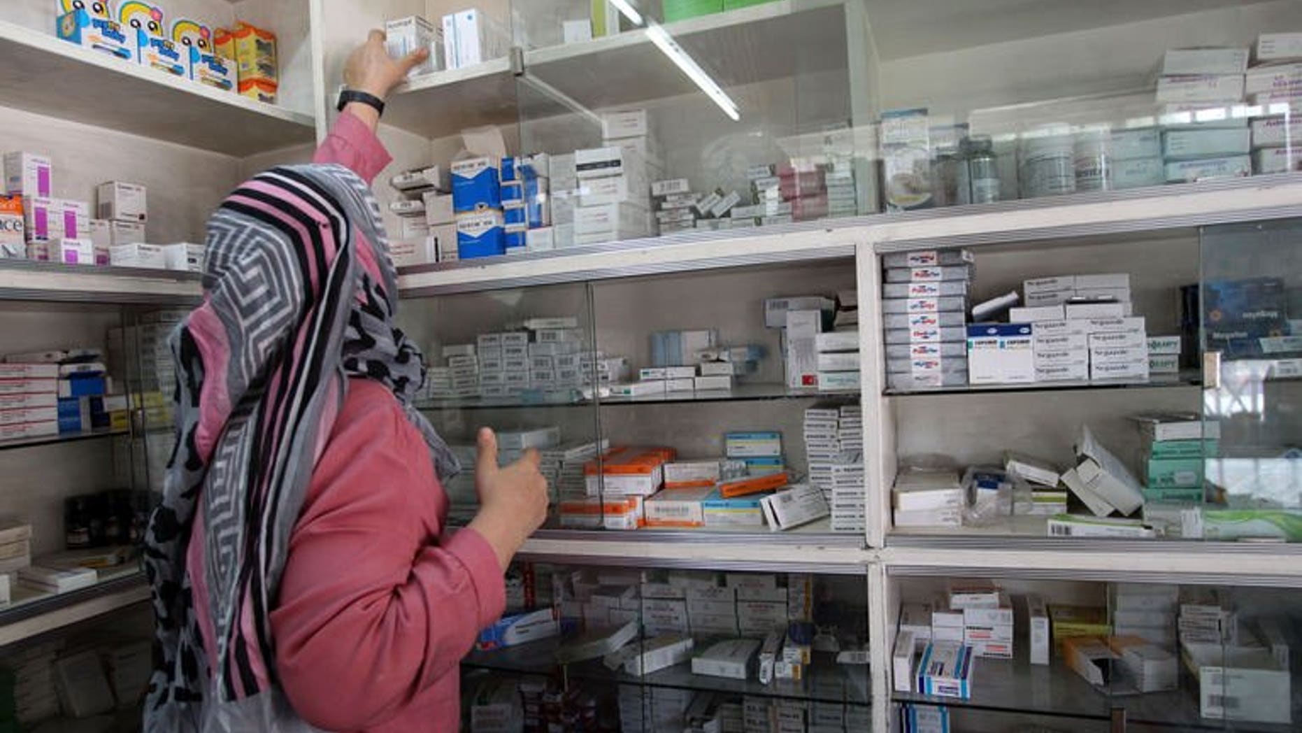 An Iraqi pharmacist arranges boxes of medicine on the shelves of her pharmacy in central Baghdad on July 30, 2013. Many Iraqis have experienced violence and suffer from war-related traumas that have scarred them for life and have forced them to rely on medicines.