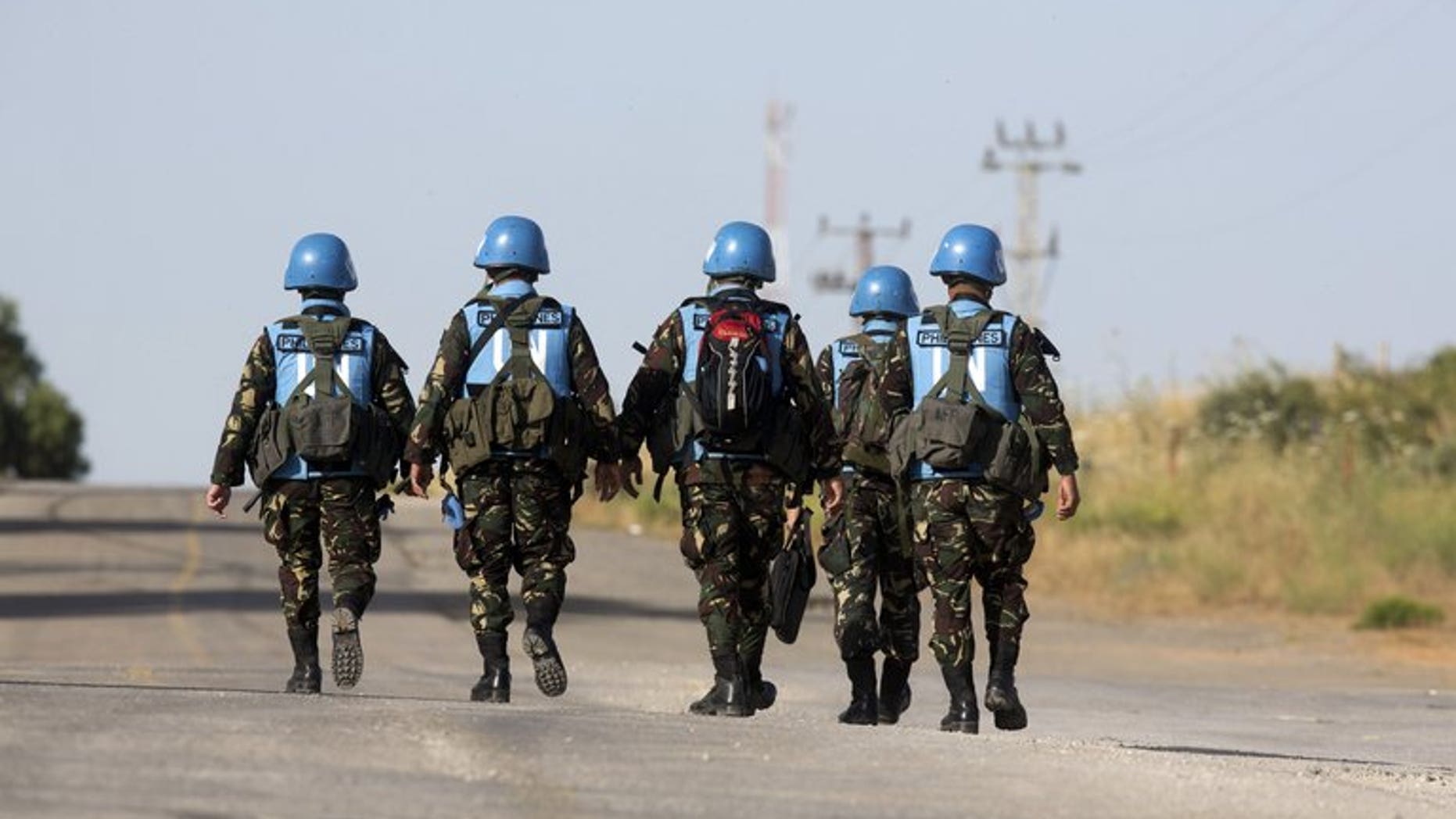 United Nations peacekeepers from the Philippines walk down a road in the Golan Heights on June 12, 2013. The Philippines said Wednesday it would likely keep its 340 soldiers in the Golan Heights as part of a United Nations peacekeeping force, amid improved security for the troops.