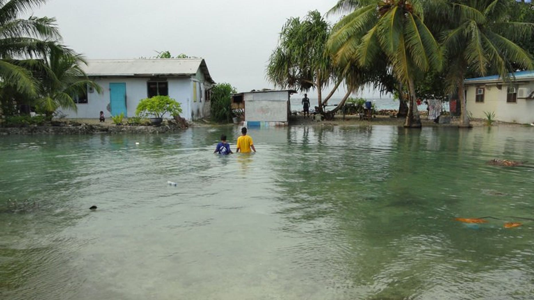 Residents wade through flooding caused by high ocean tides in low-lying parts of Majuro Atoll, the capital of the Marshall Islands, on February 20, 2011. The Marshall Islands has warned of a Pacific "climate catastrophe" that will wipe it off the map without decisive action on global warming, saying the next 12 months are critical.